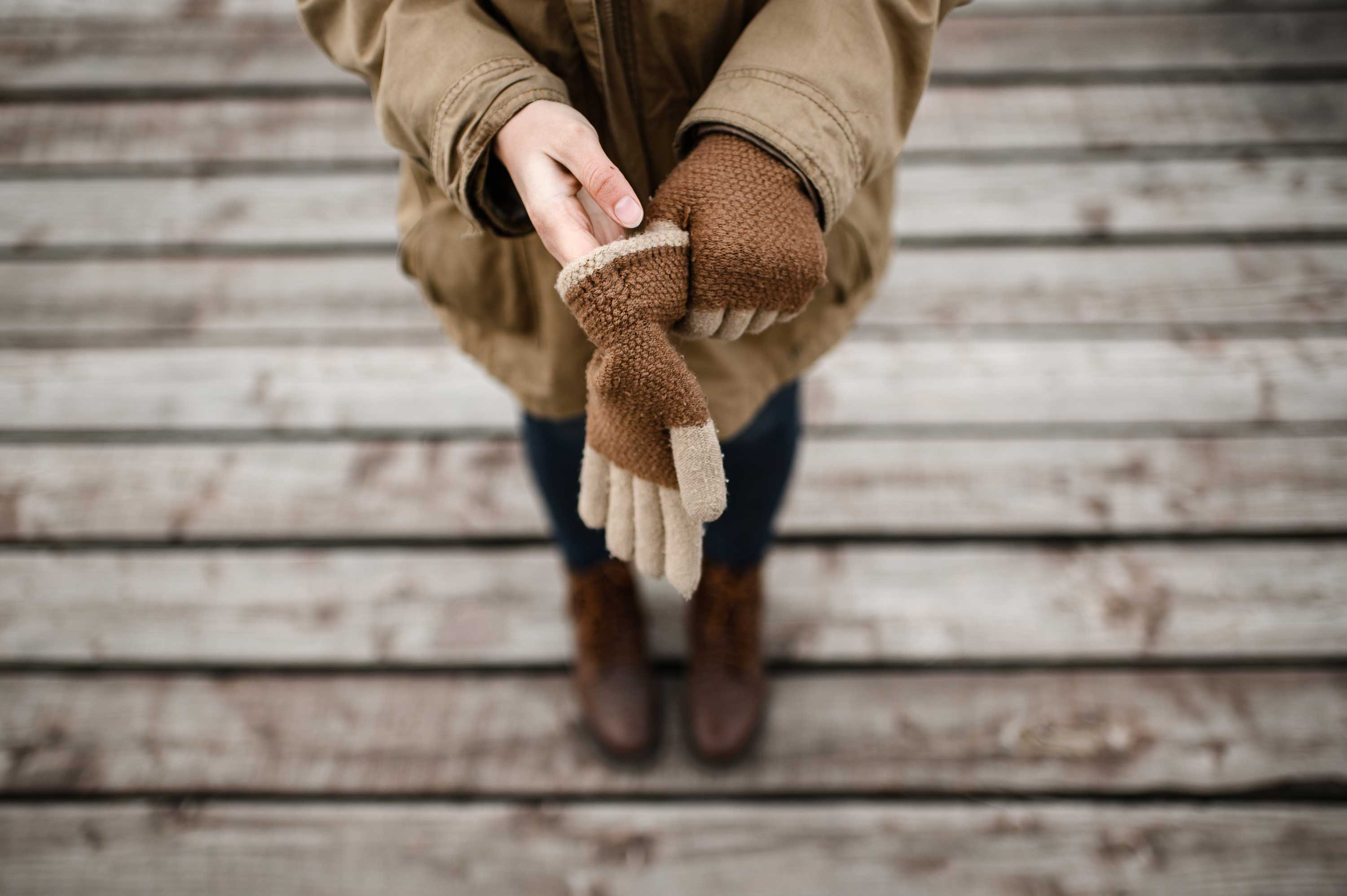 A woman puts on brown gloves.