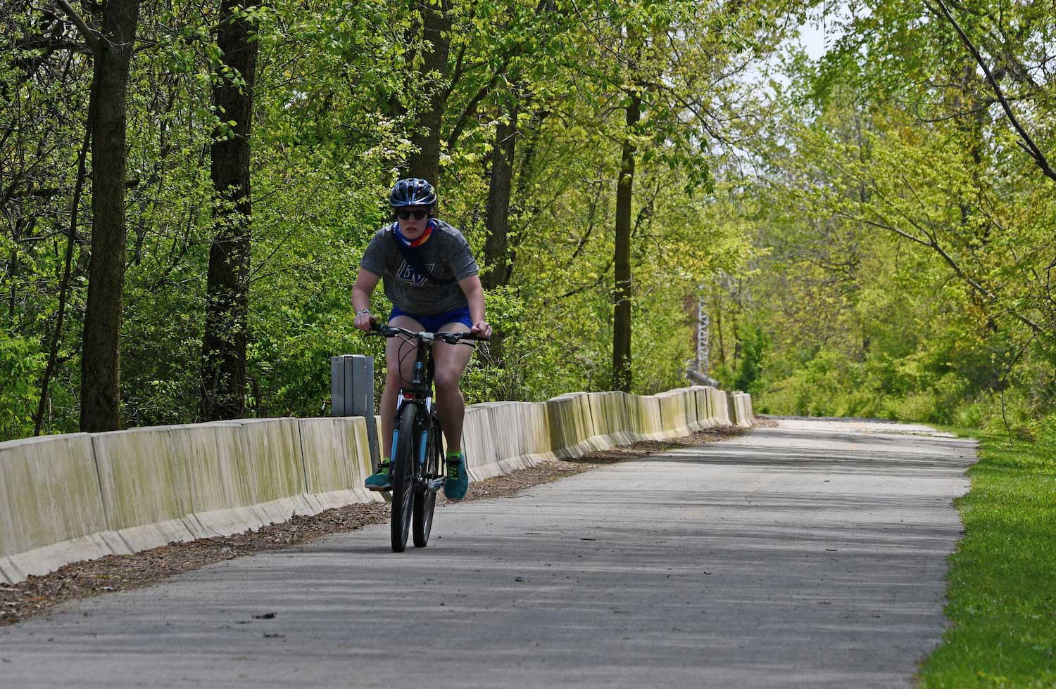A person riding a bike along a paved trail.