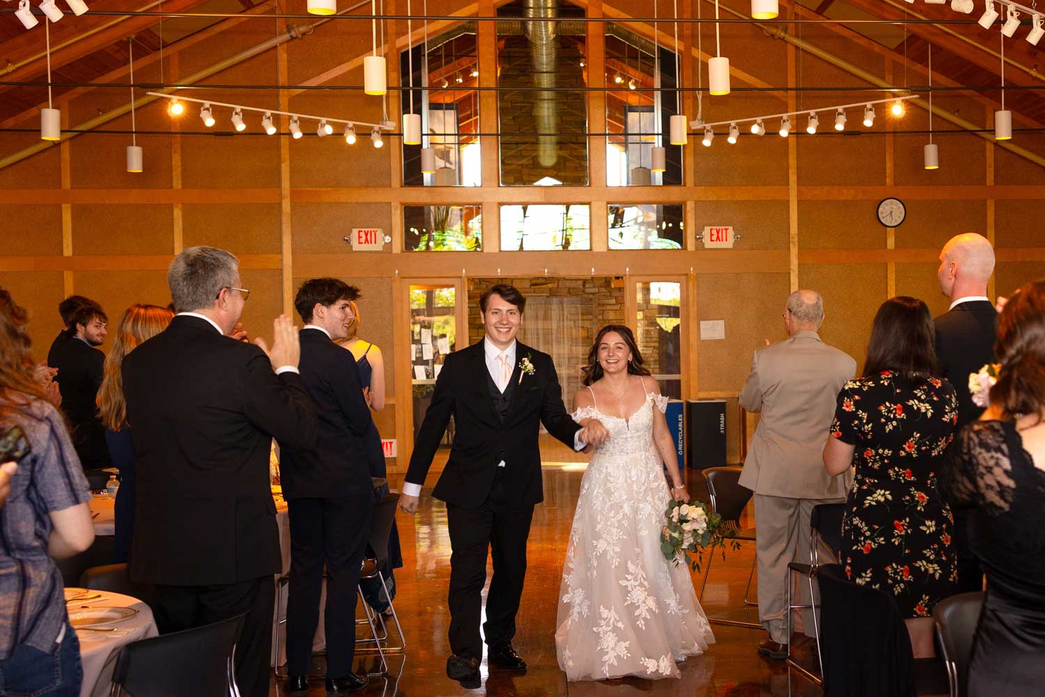 Newly married couple walking down aisle past guests.