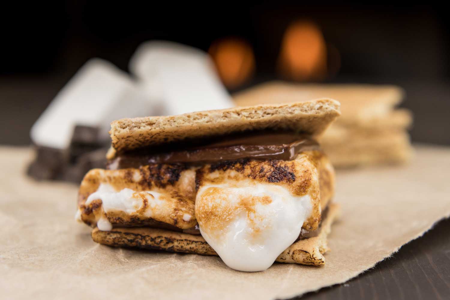 A s'more with oozing melted marshmallows sitting on a table.