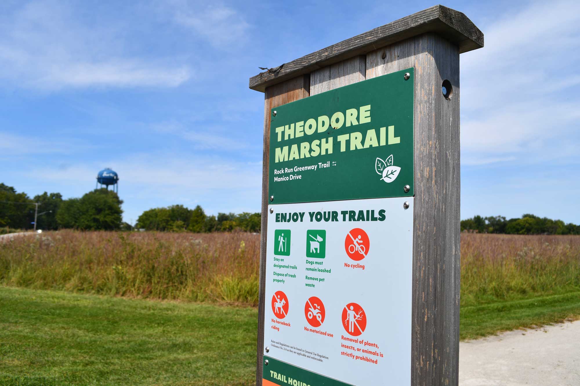 Trail sign with vegetation in the background.