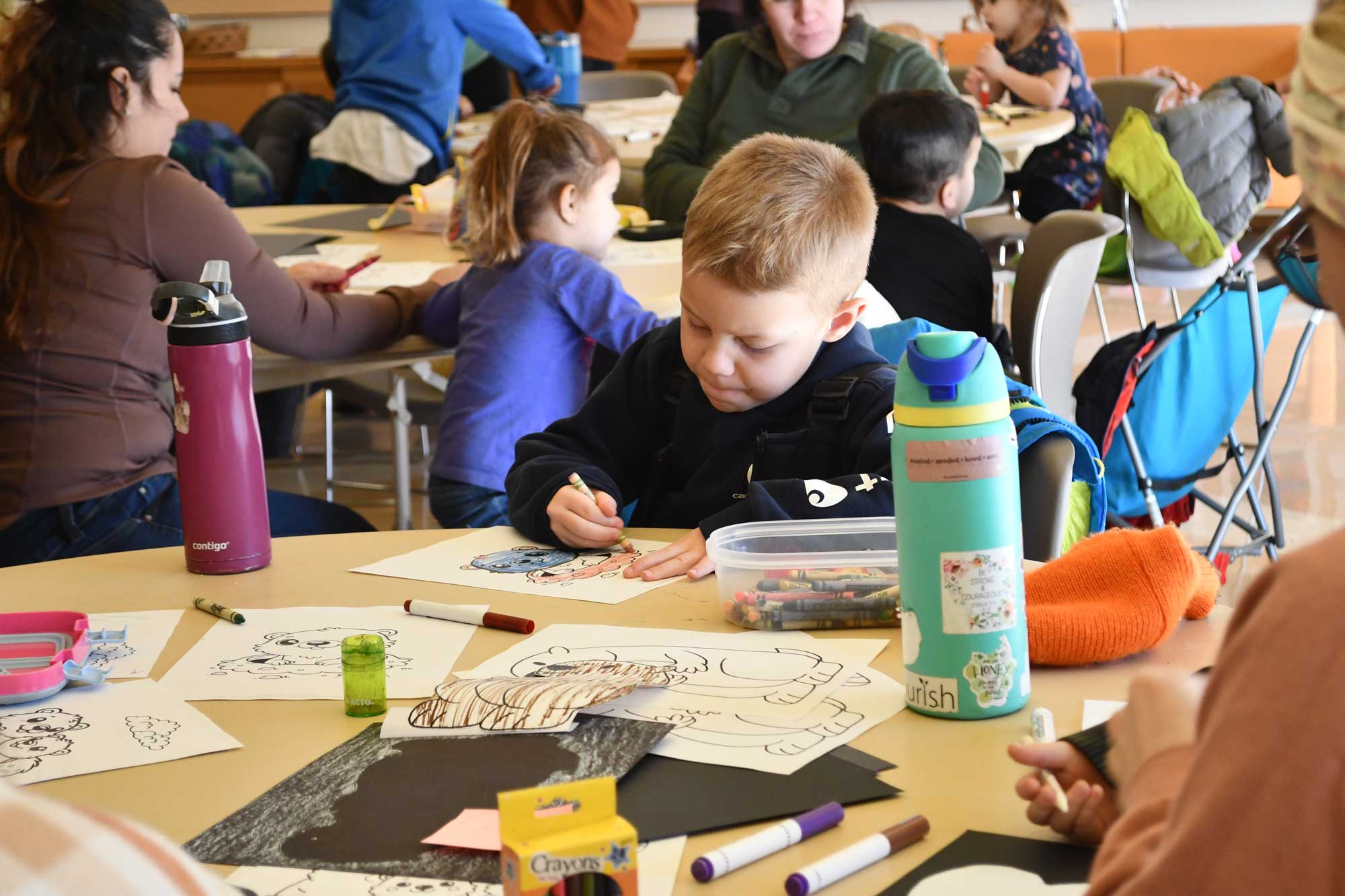 A child coloring while sitting at a tablee.