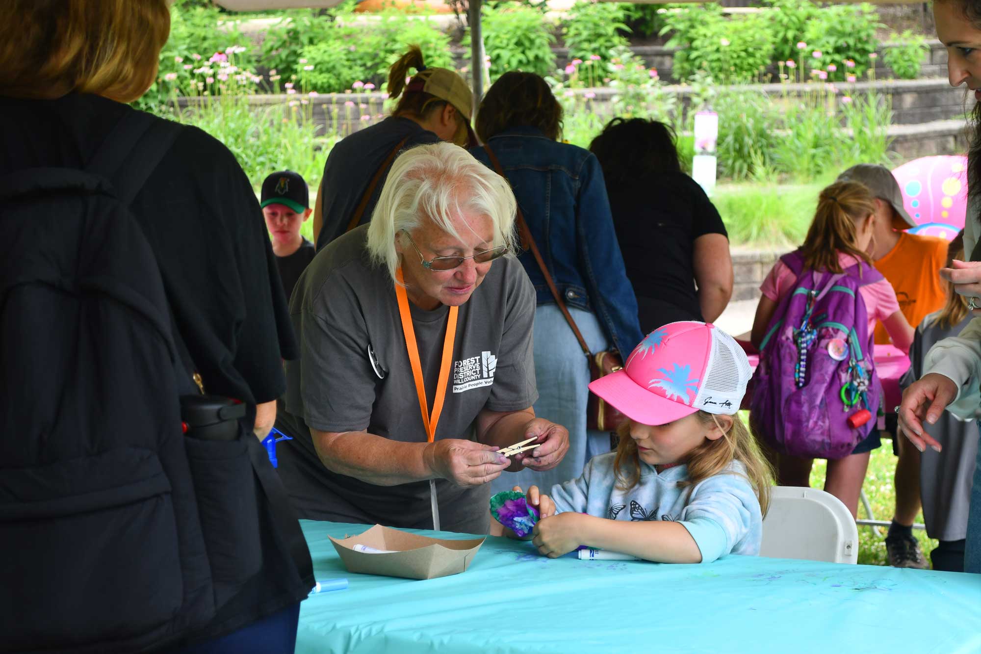 Person helping a child with a craft at a program.