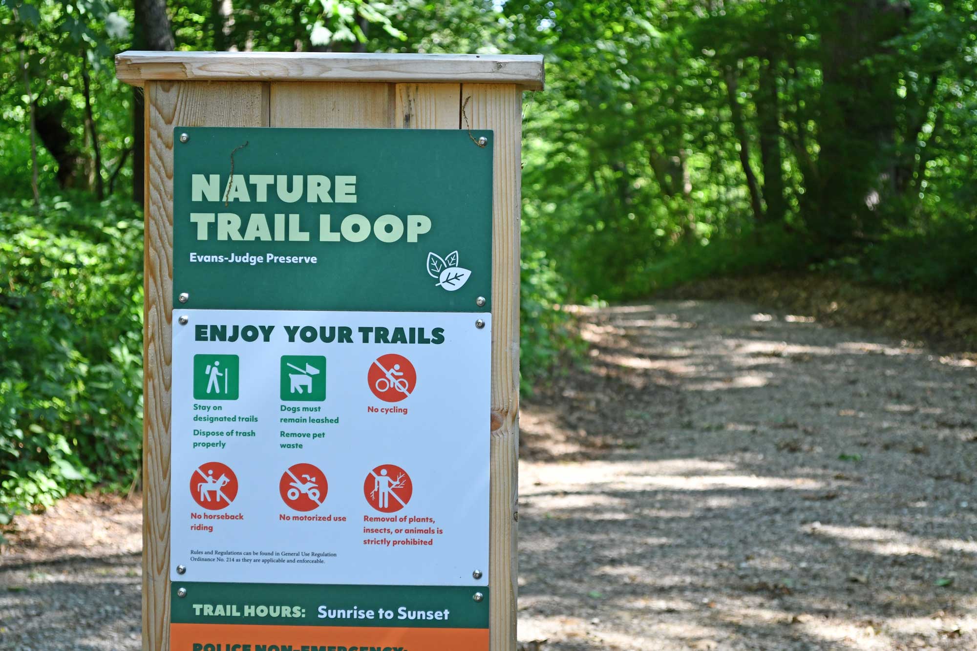 Trail sign in front of a gravel trail.