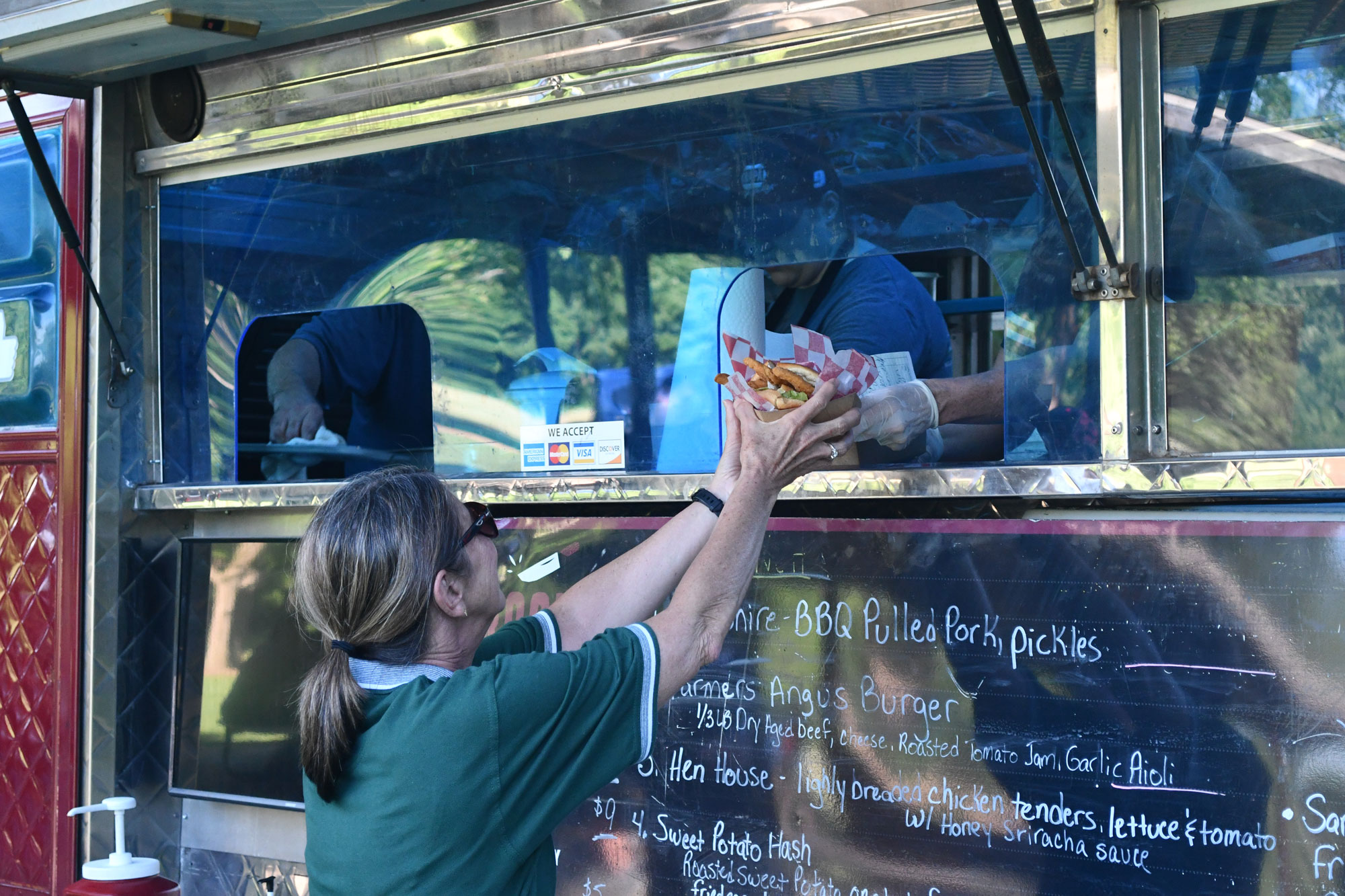 A person reaching up to receive food from the window of a food truck.
