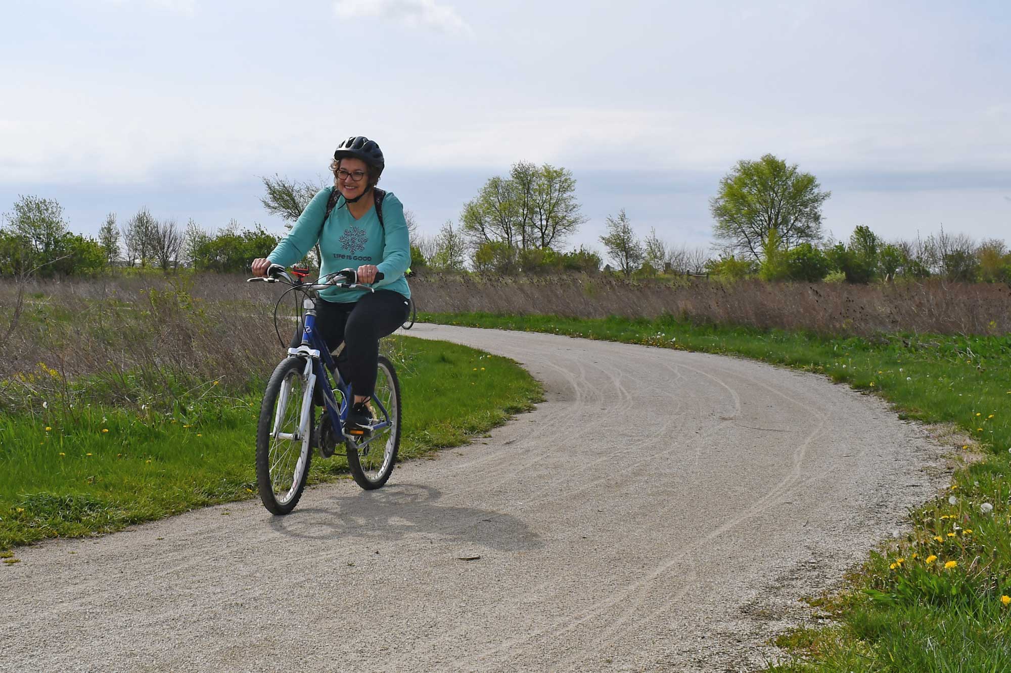Person biking on a limestone trail with vegetation in the background.