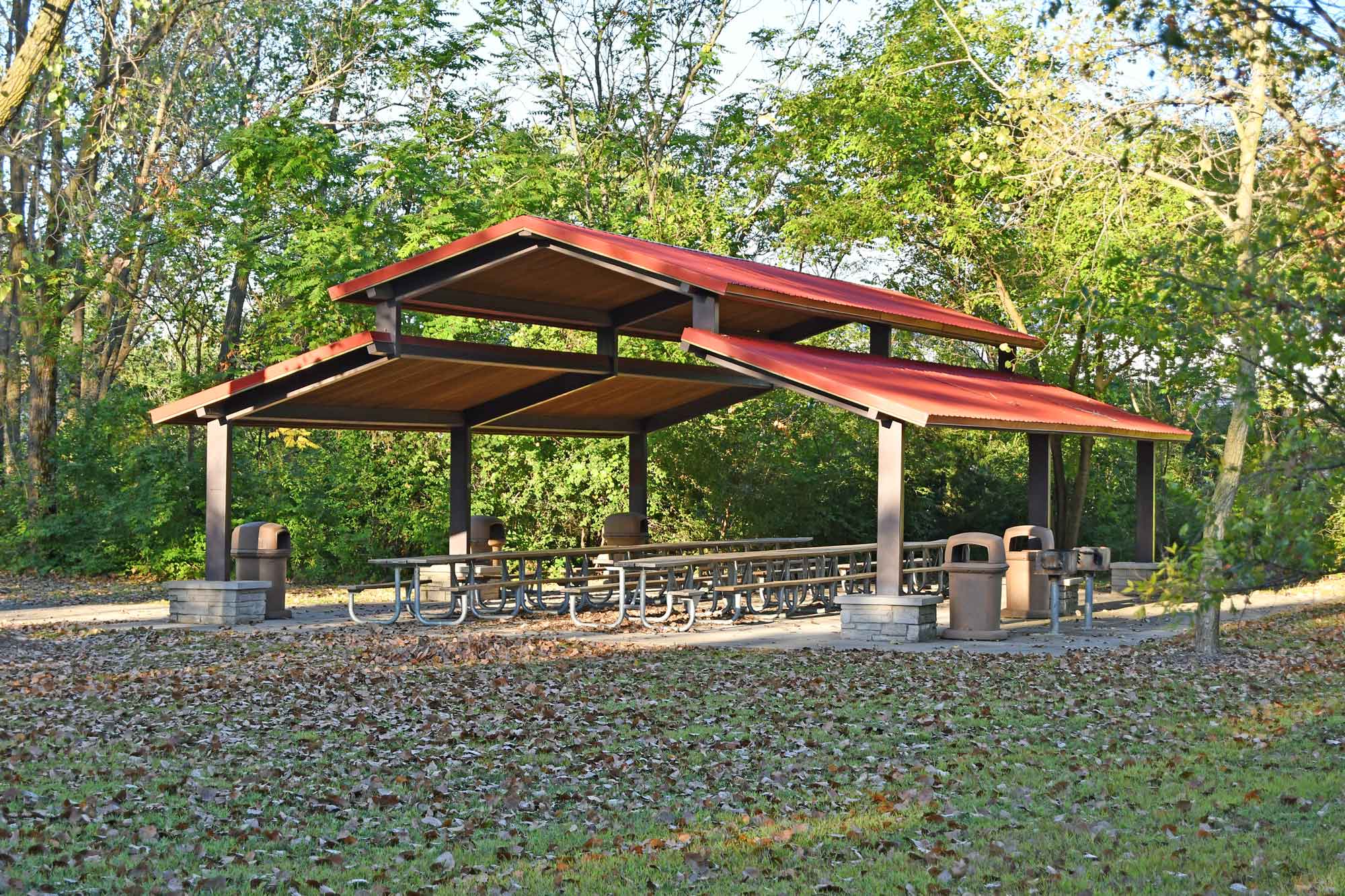 a picnic area with picnic tables and trash cans