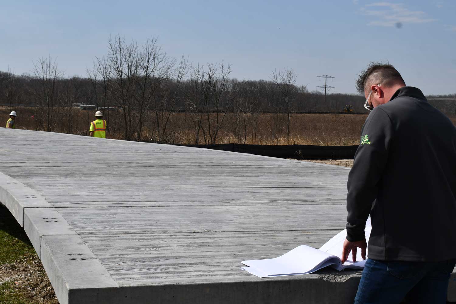 Person going over construction plans with trail being worked on.