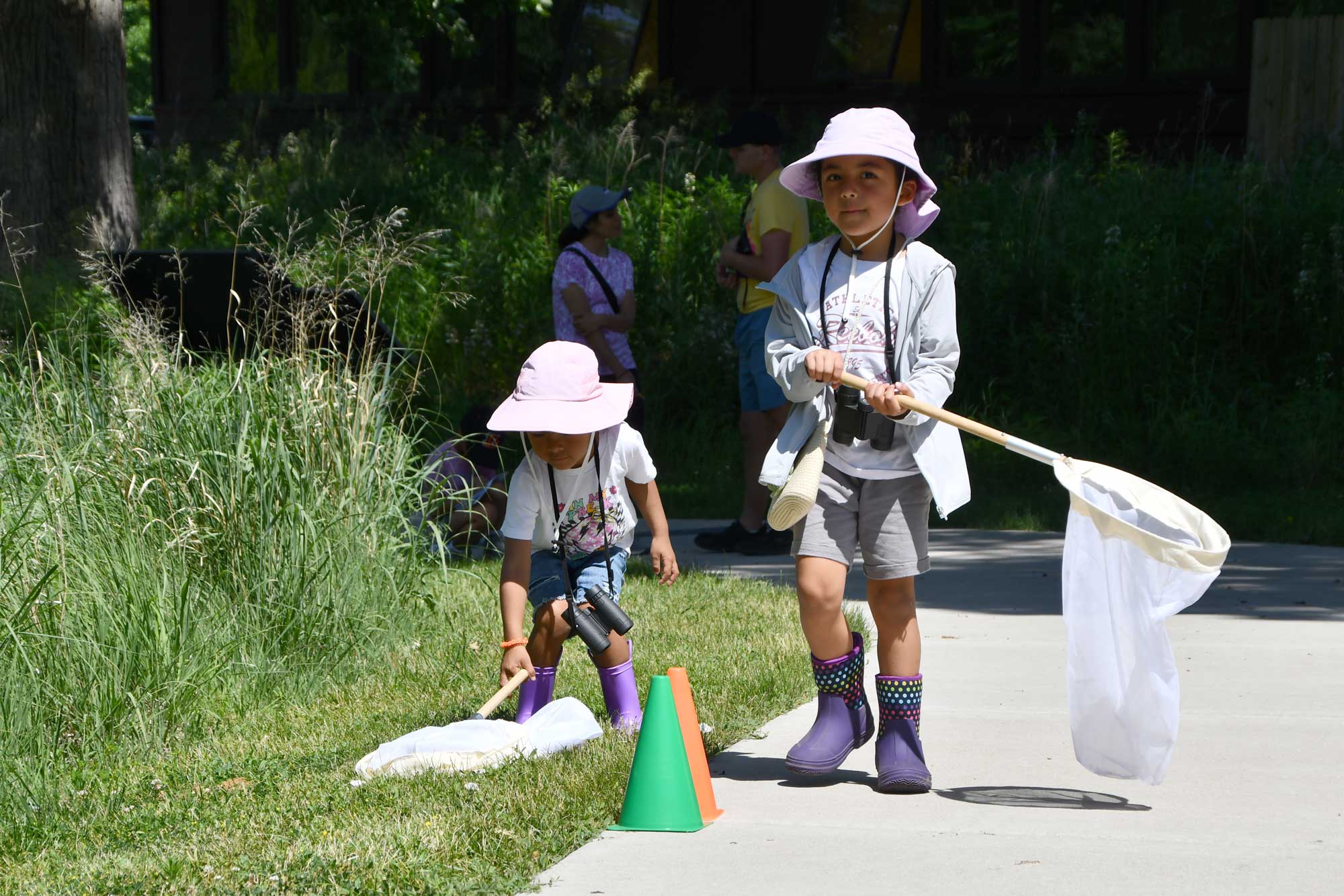 Two children holding insect nets walking along a trail. 