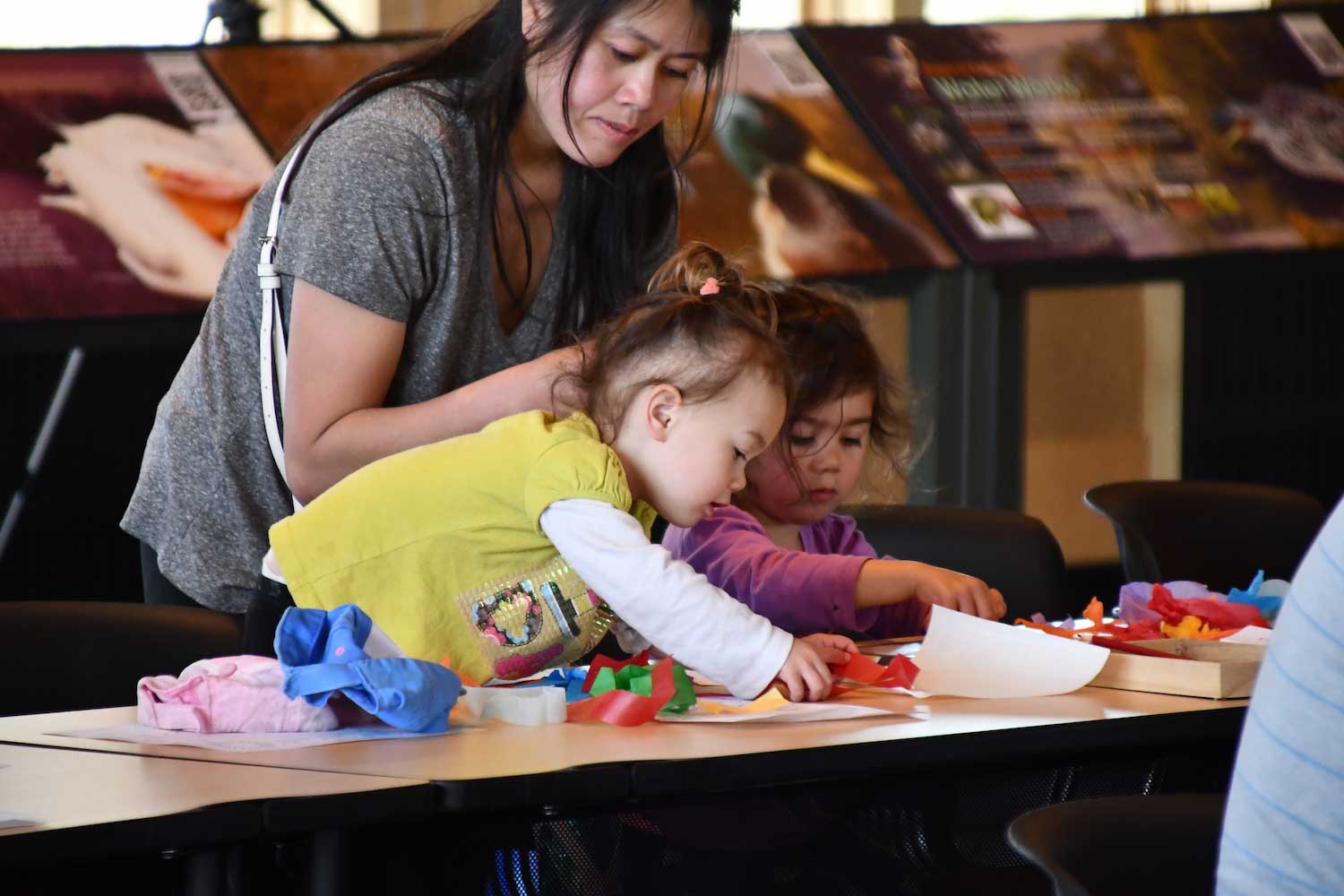 Two kids and an adult working on an activity at a table. 