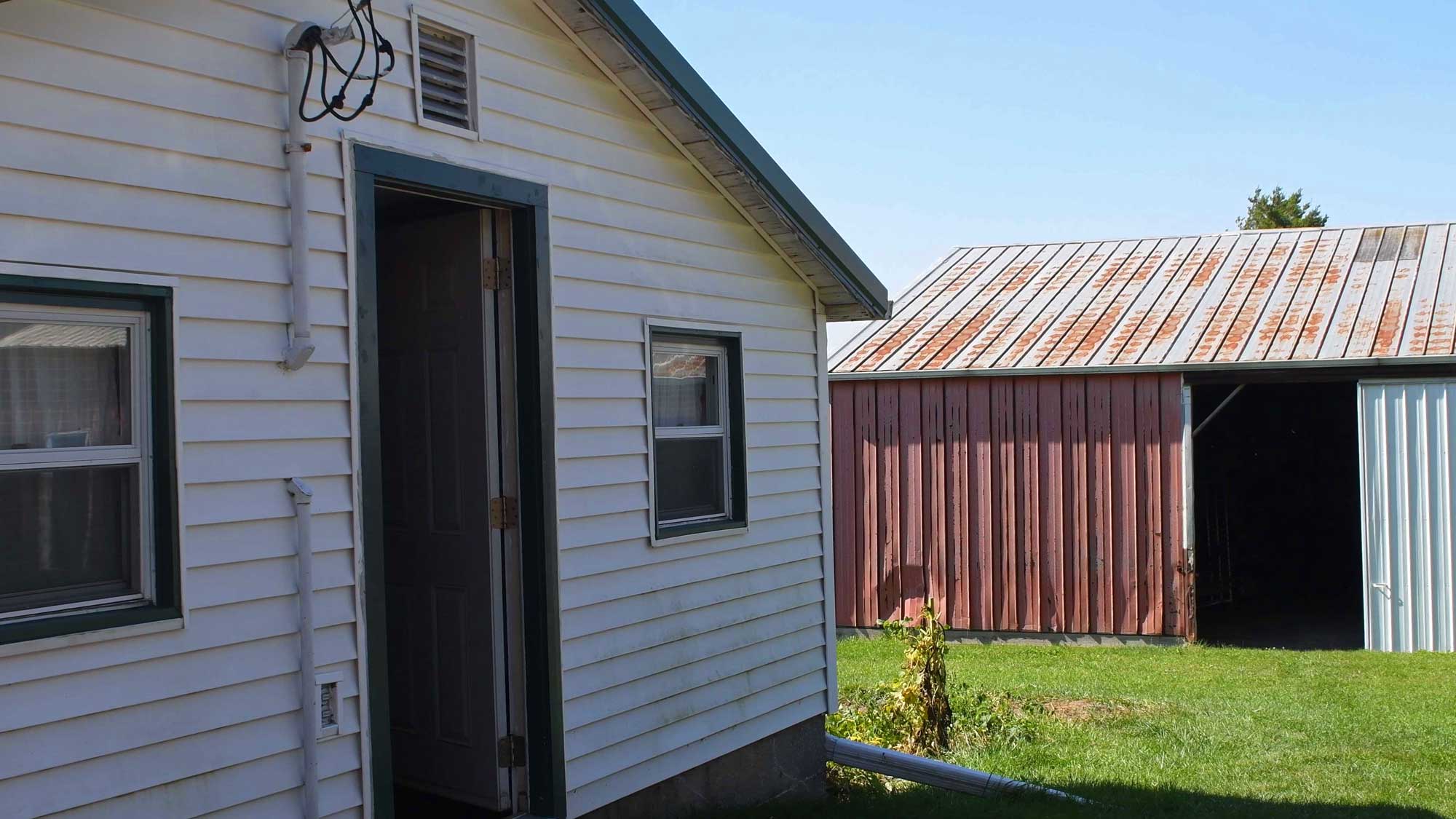 Chicken coop in front of an implement shed.