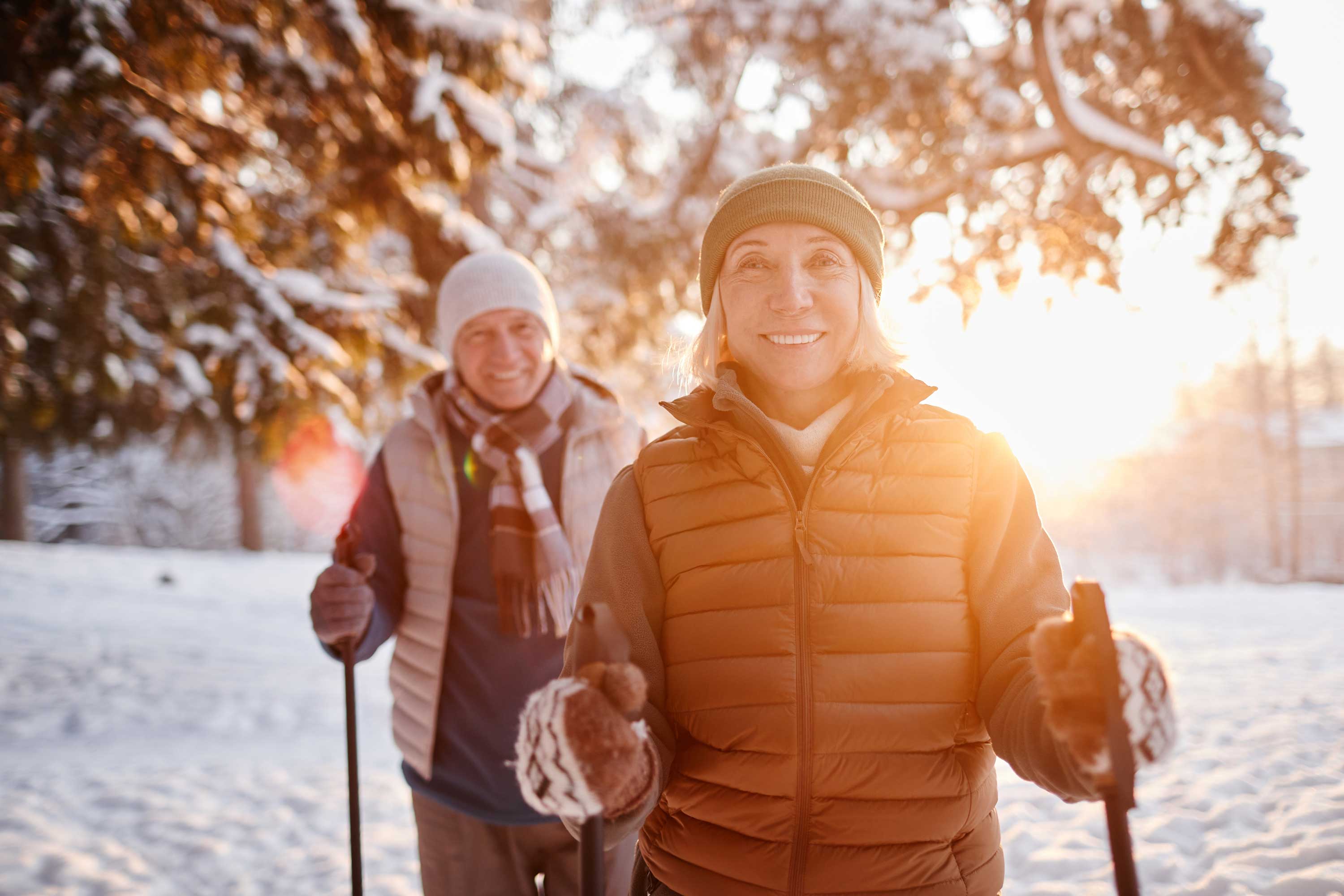 An elderly couple bundled up on a trail while cross country skiing.