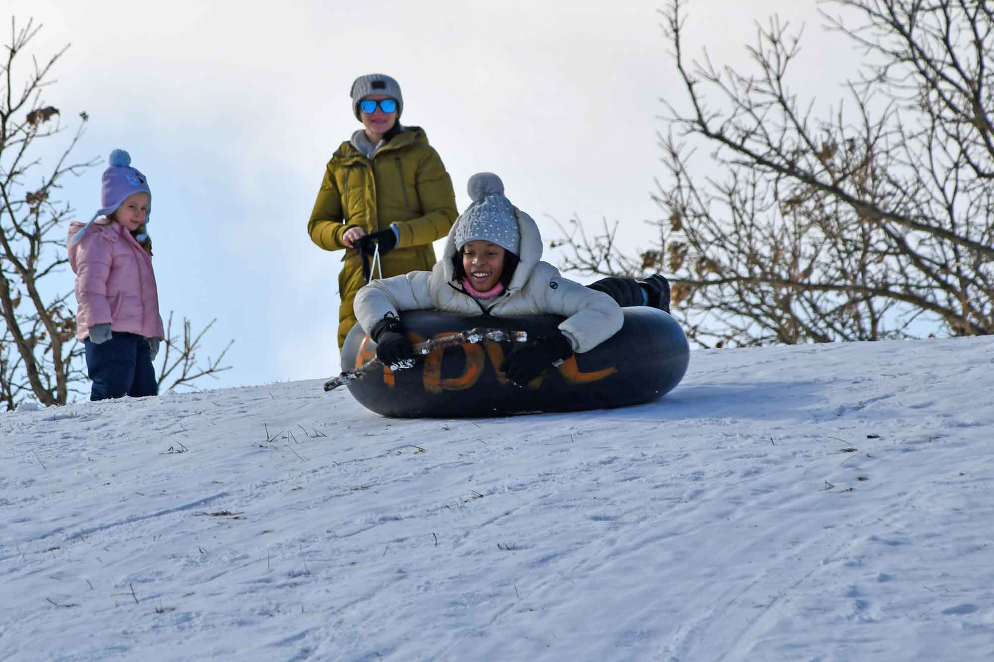 a woman and a girl on a snow tube