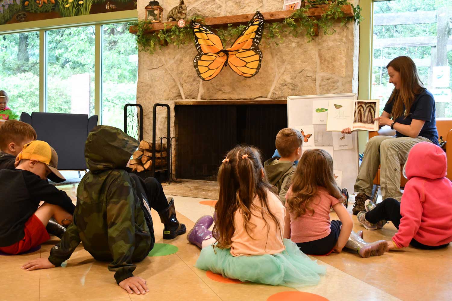 A group of kids sitting on the floor listening while an adult reads them a story.
