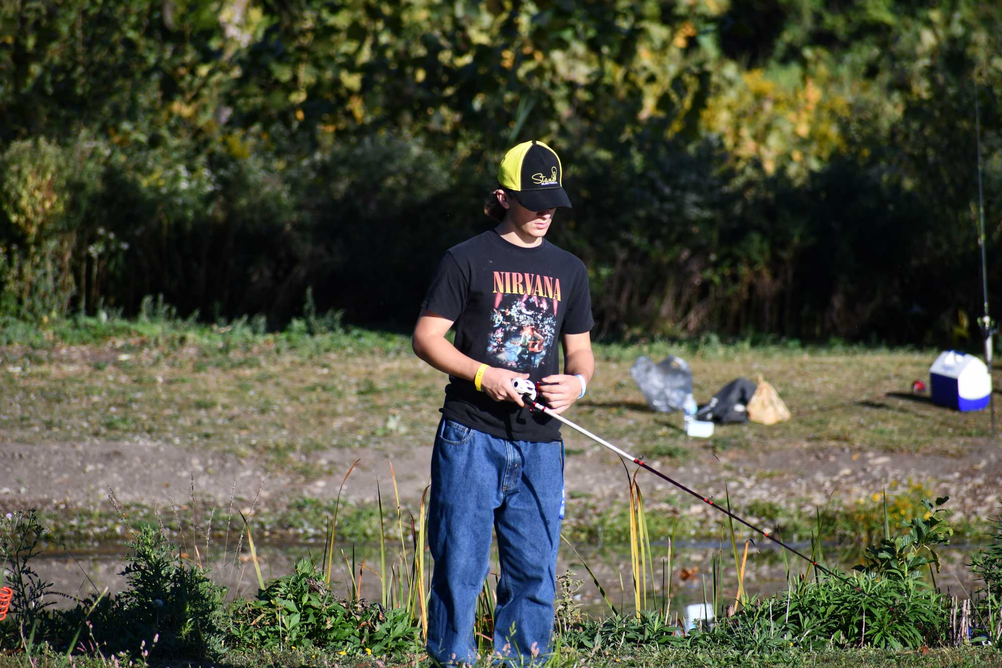 A person holding a fishing pole while fishing along a shoreline.