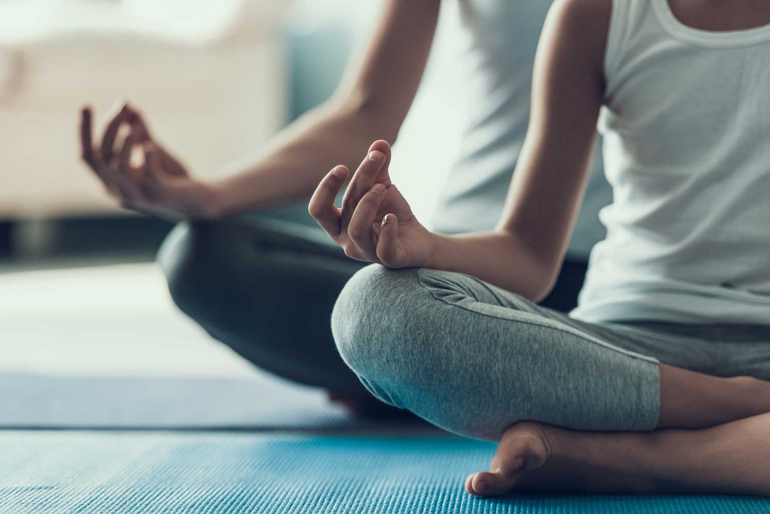 Two people sitting cross legged in a yoga pose.