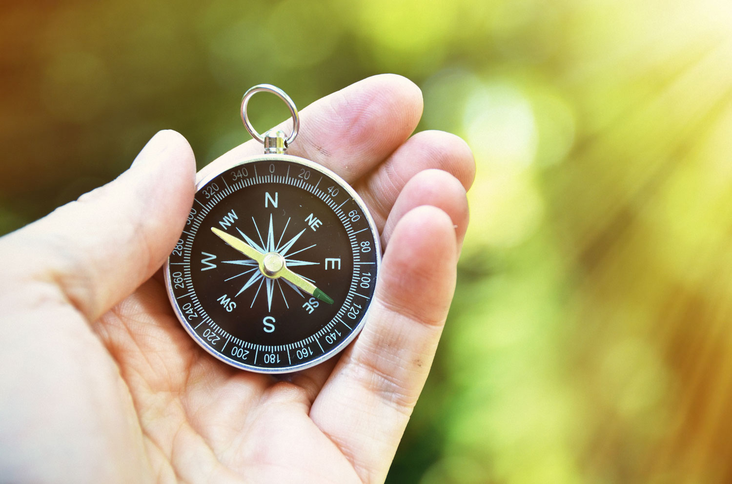 A close-up of a black compass being held by hand.