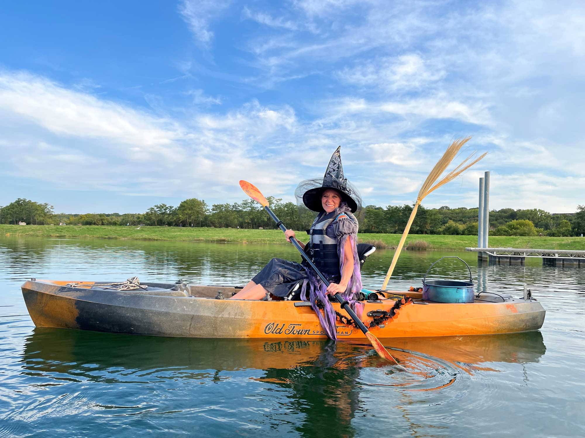 A person wearing a witch costume in a kayak on water.