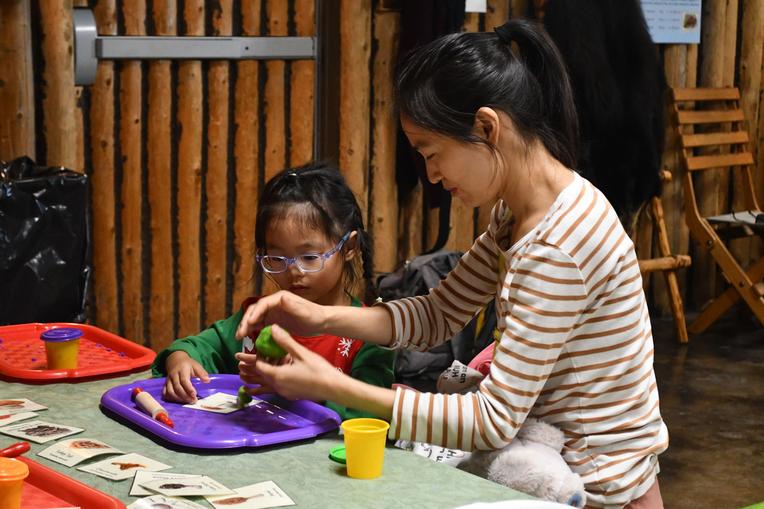 Ann adult and child working on a craft on a tray while sitting at a table.