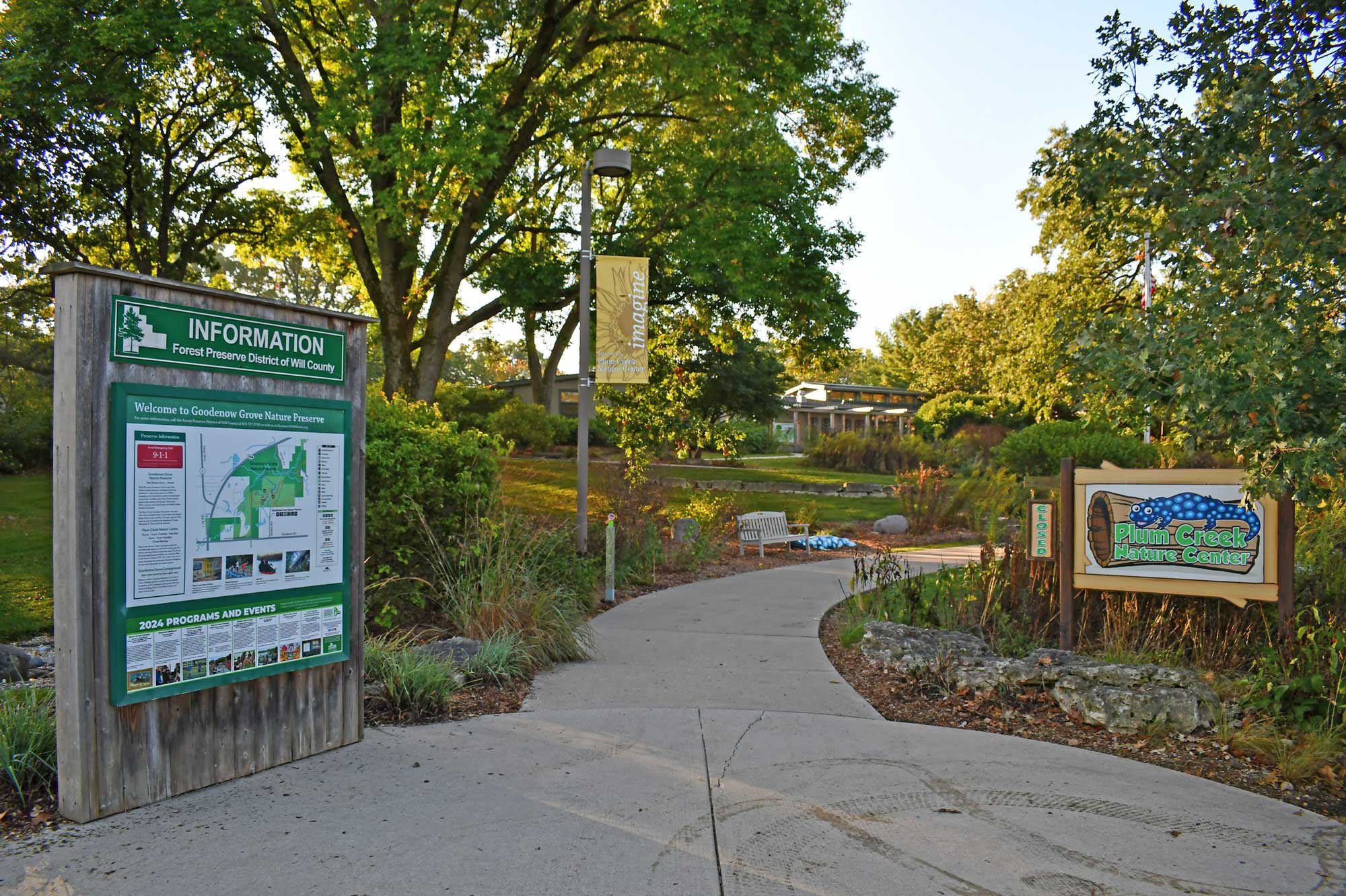 Nature center sign and entrance walkway with trees in the background.