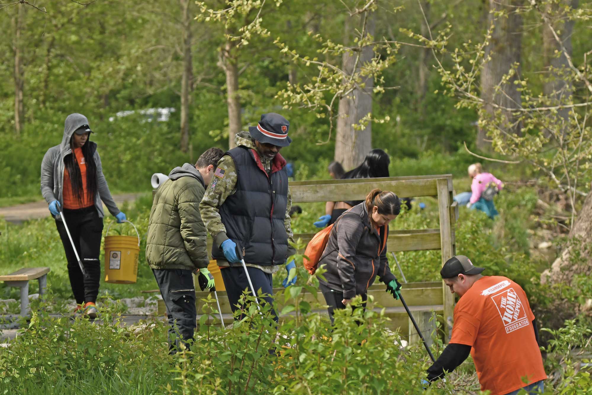 People picking up trash in a preserve near a trail.