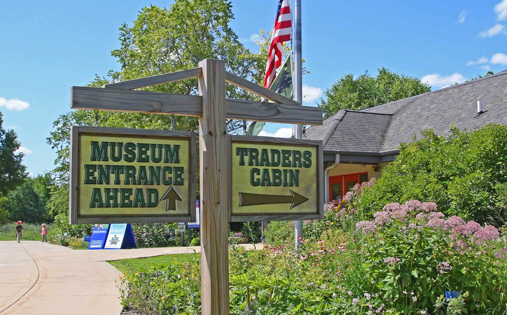 Sign outside of museum with vegetation and the building in the background.
