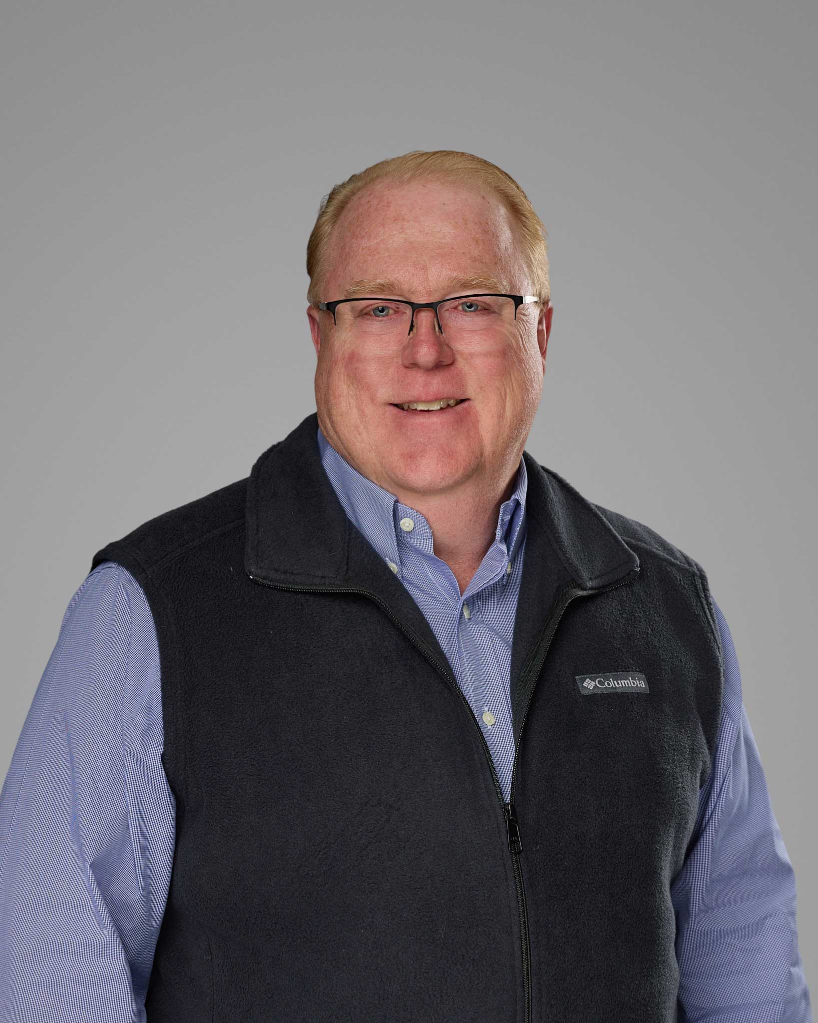 a man wearing glasses and a vest