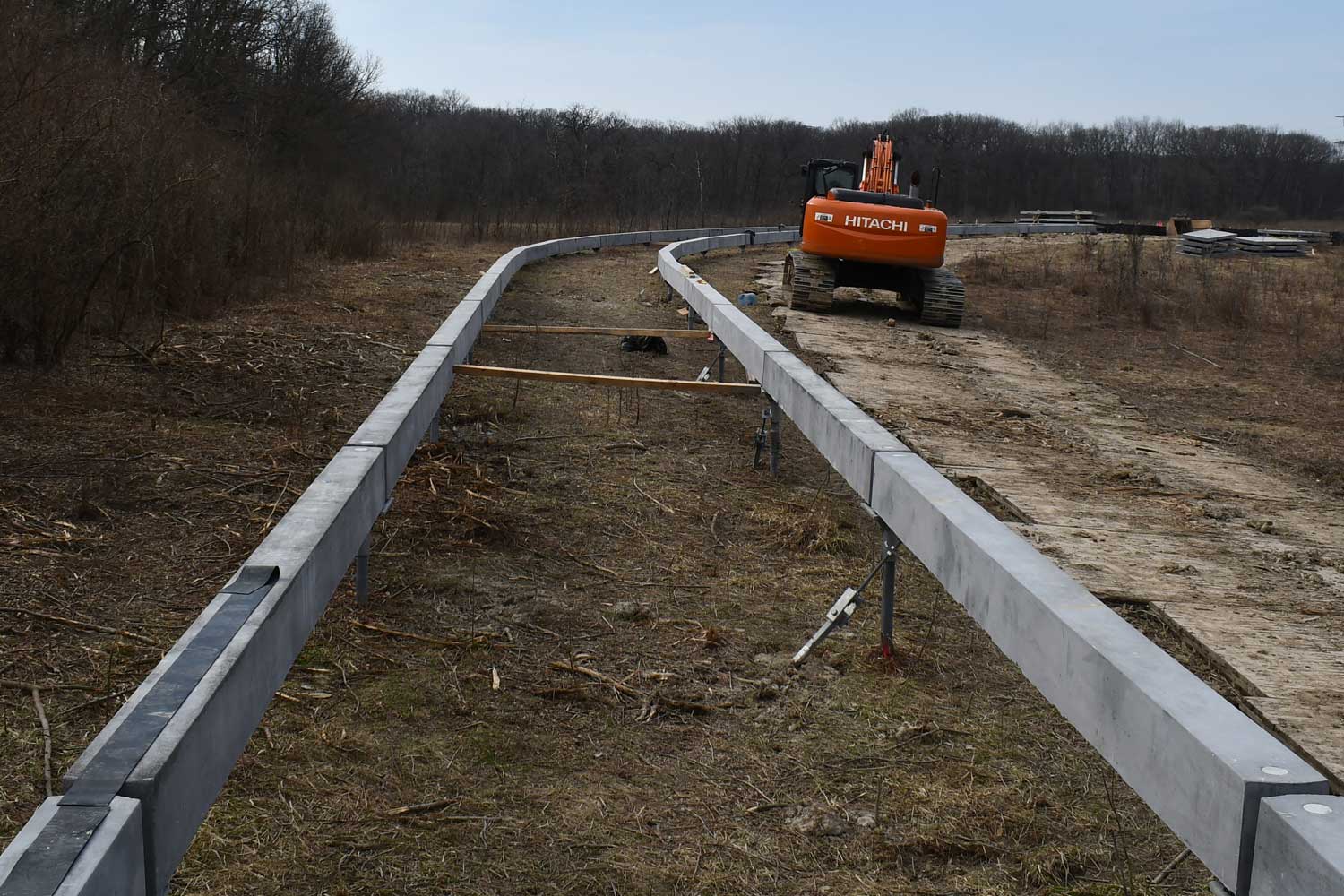 Construction vehicle next to construction being done along a trail.
