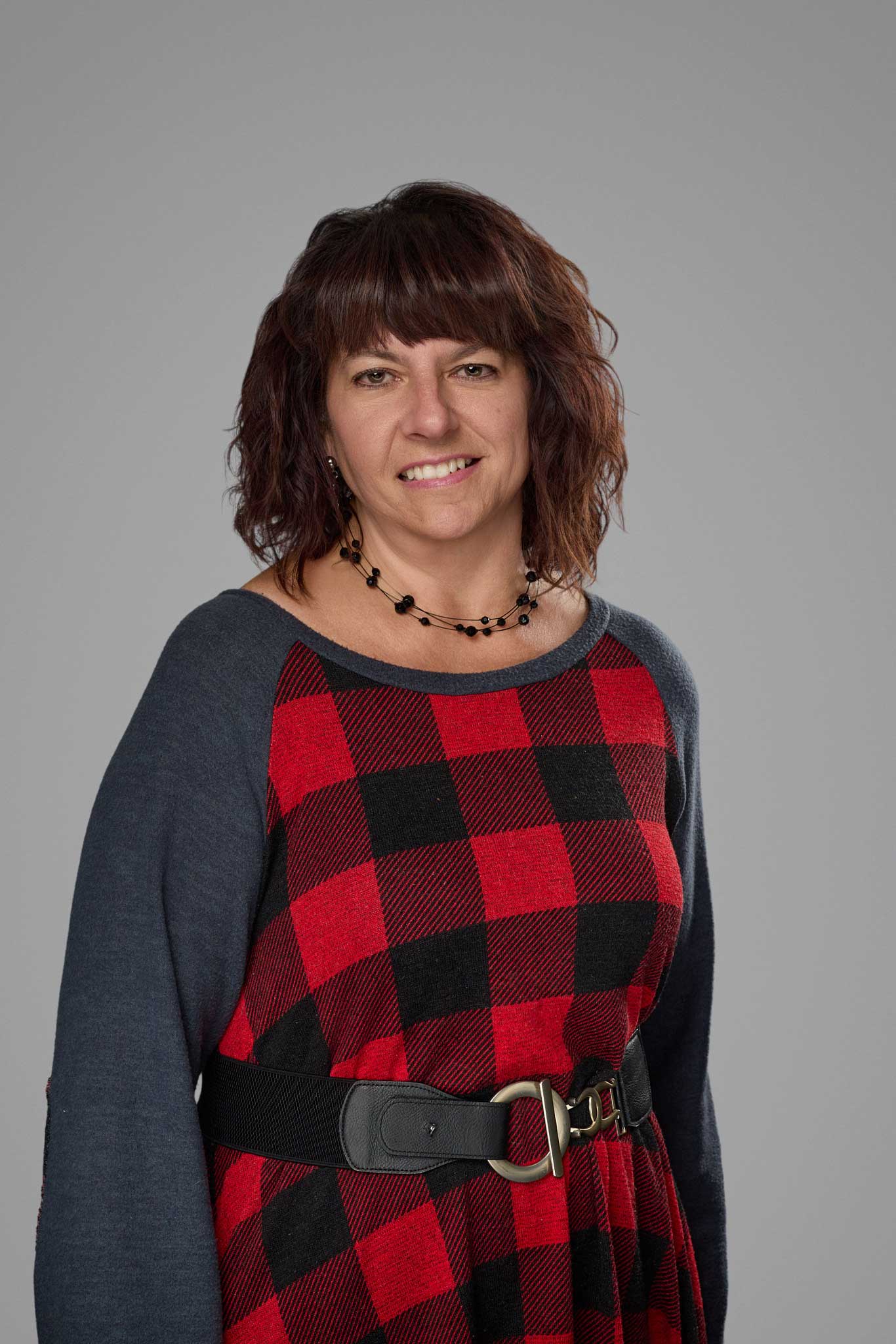 a woman with brown hair wearing a red and black plaid shirt