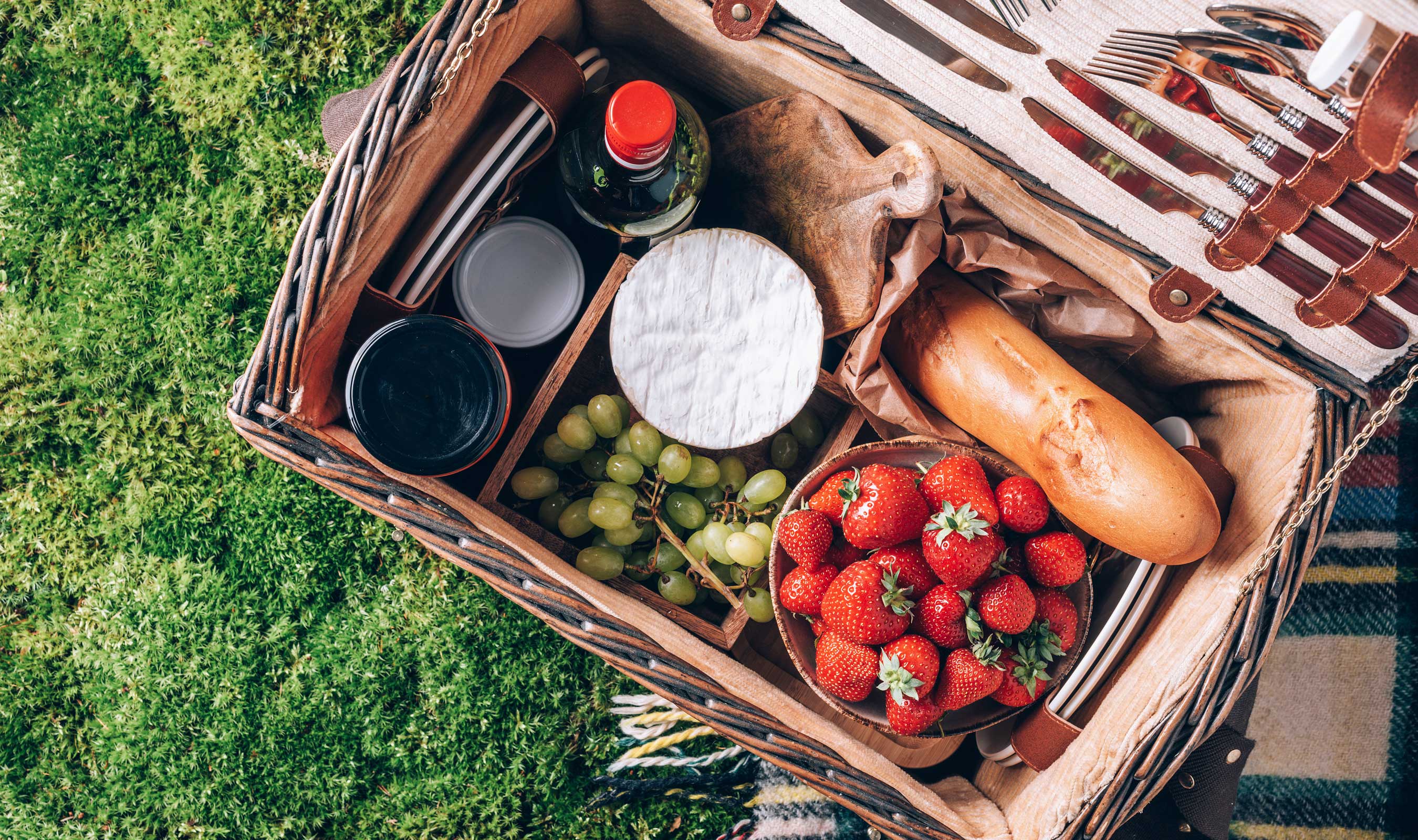 a basket with food and drinks on the grass