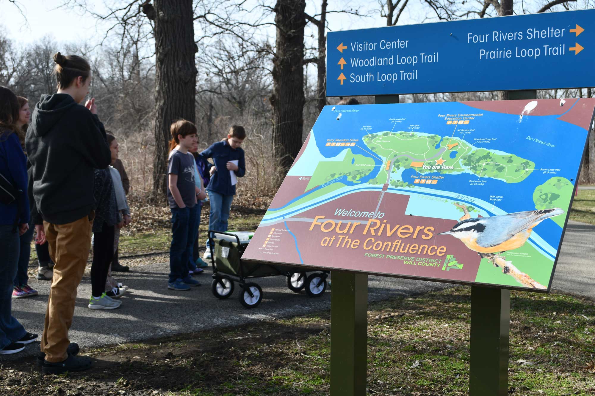 Trail signage with visitors and trees in the background.
