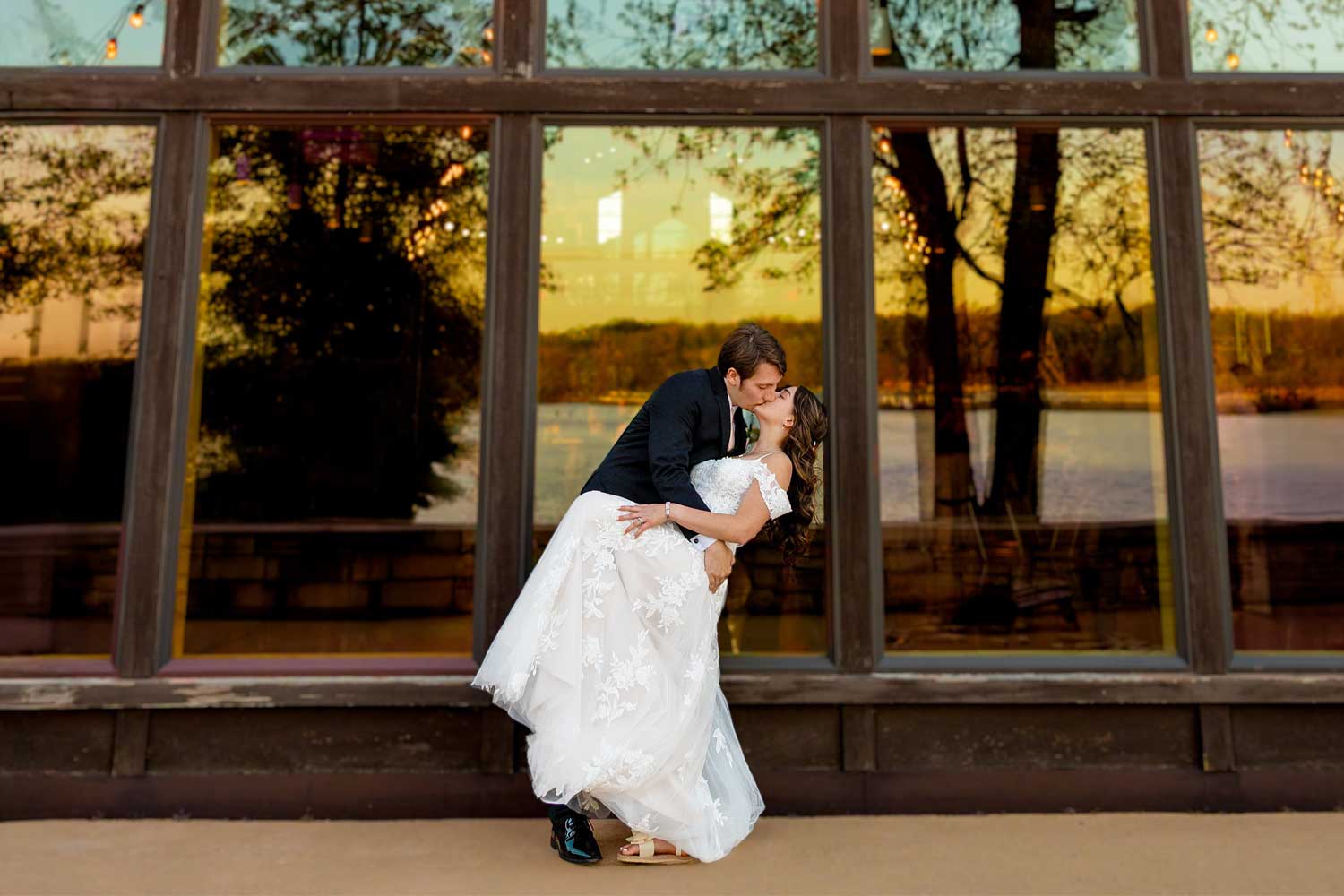 Newly married couple sharing a kiss in front of a venue.