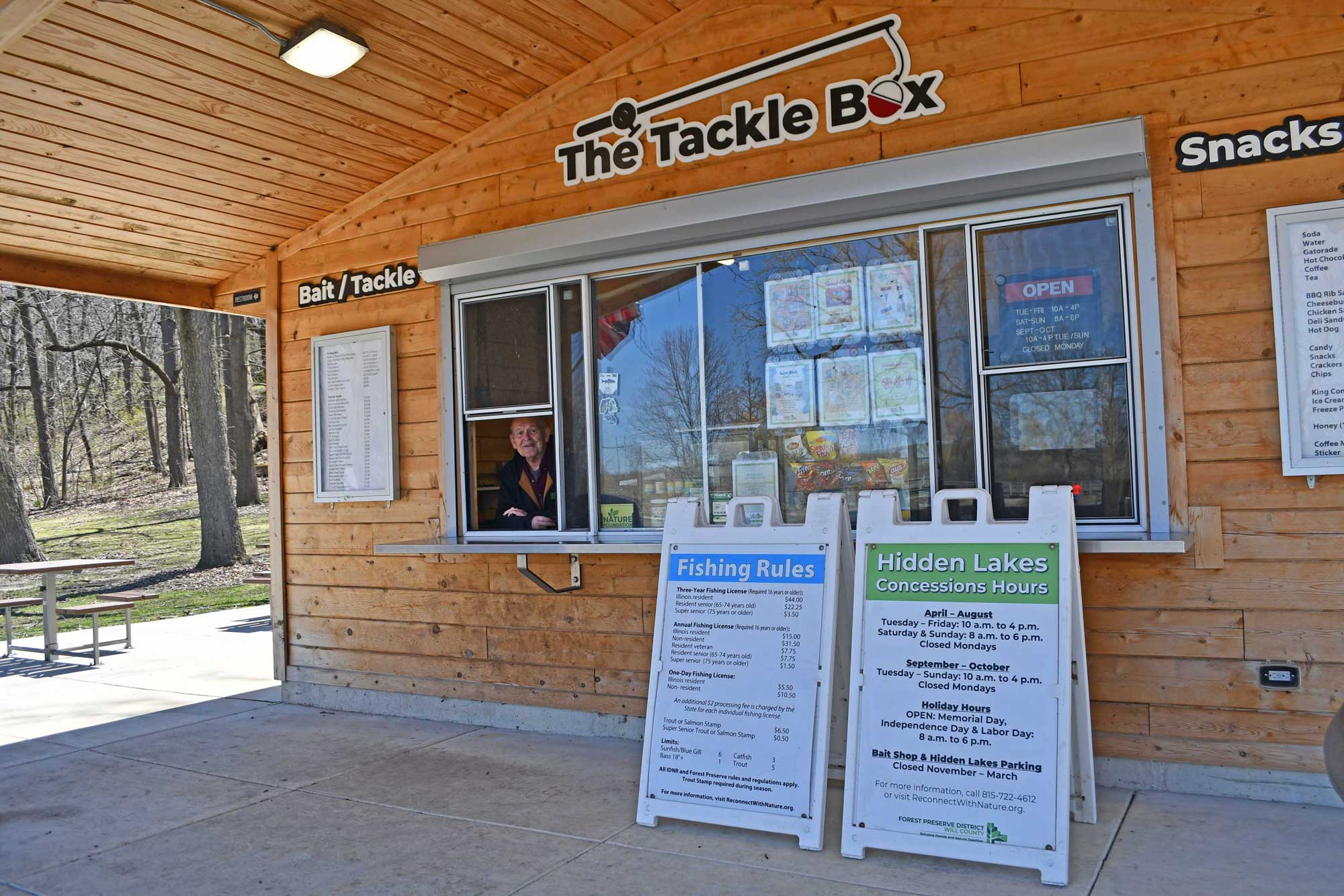 Bait stand with signage and trees in the background.