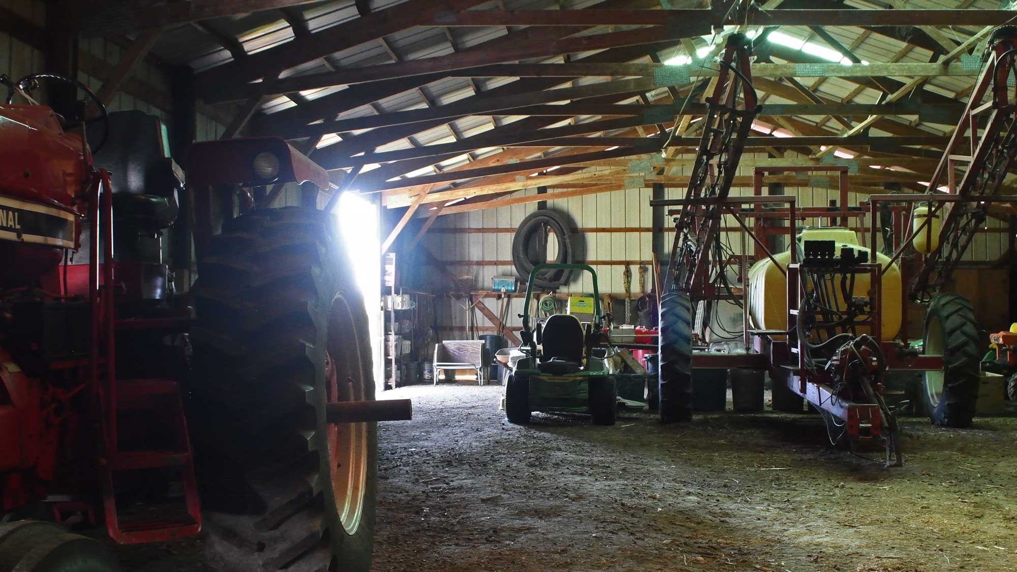 Farming vehicles sitting idle in an implement shed.