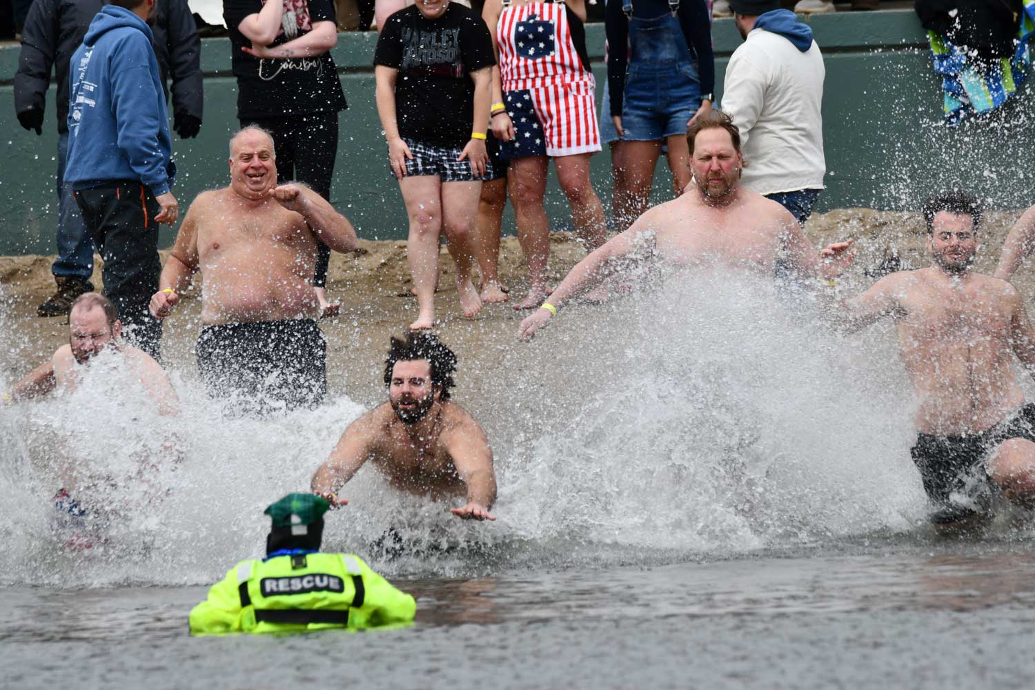 People dive into water along a beach
