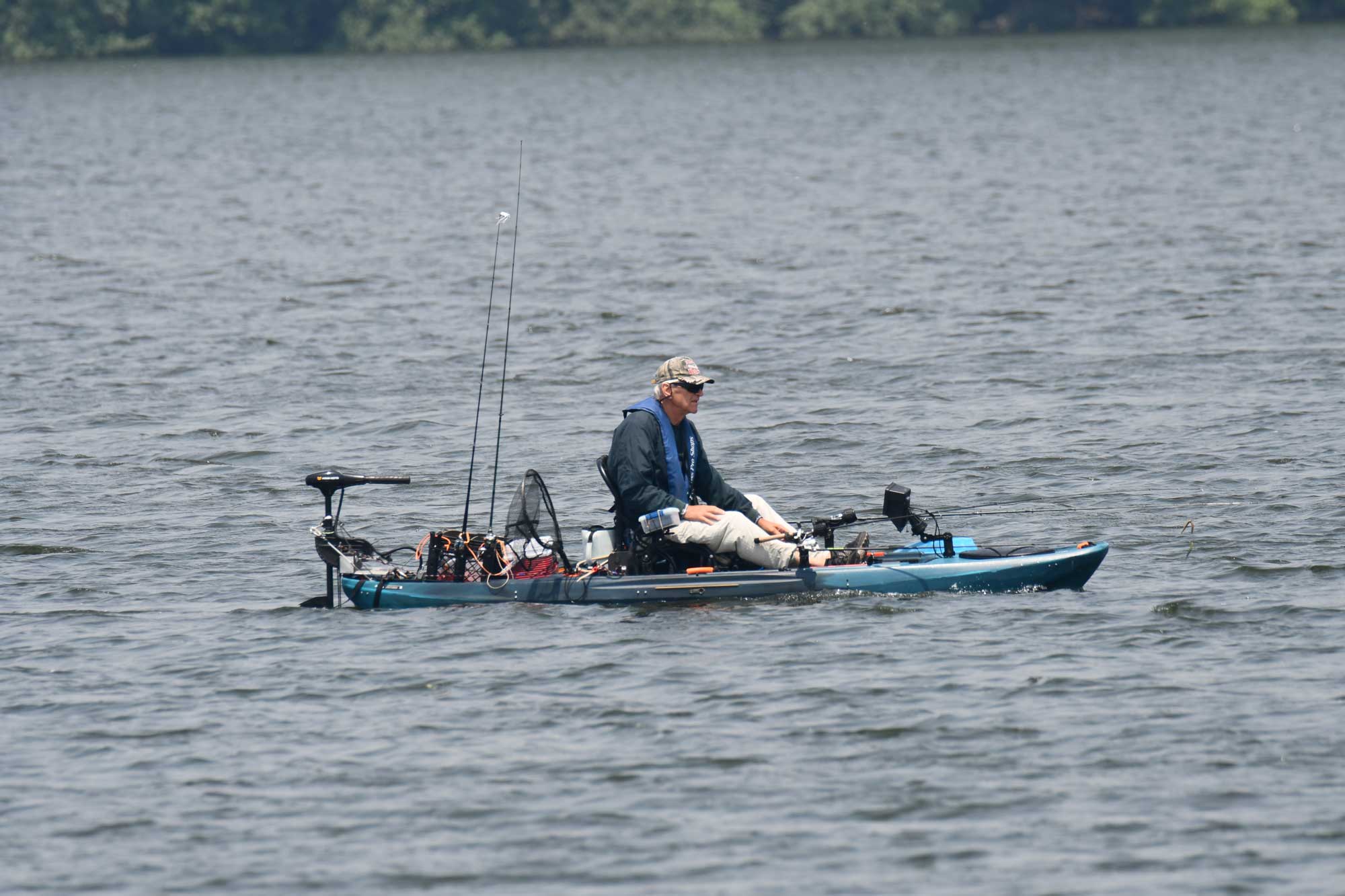 Person sitting in a boat with water and trees in the background.