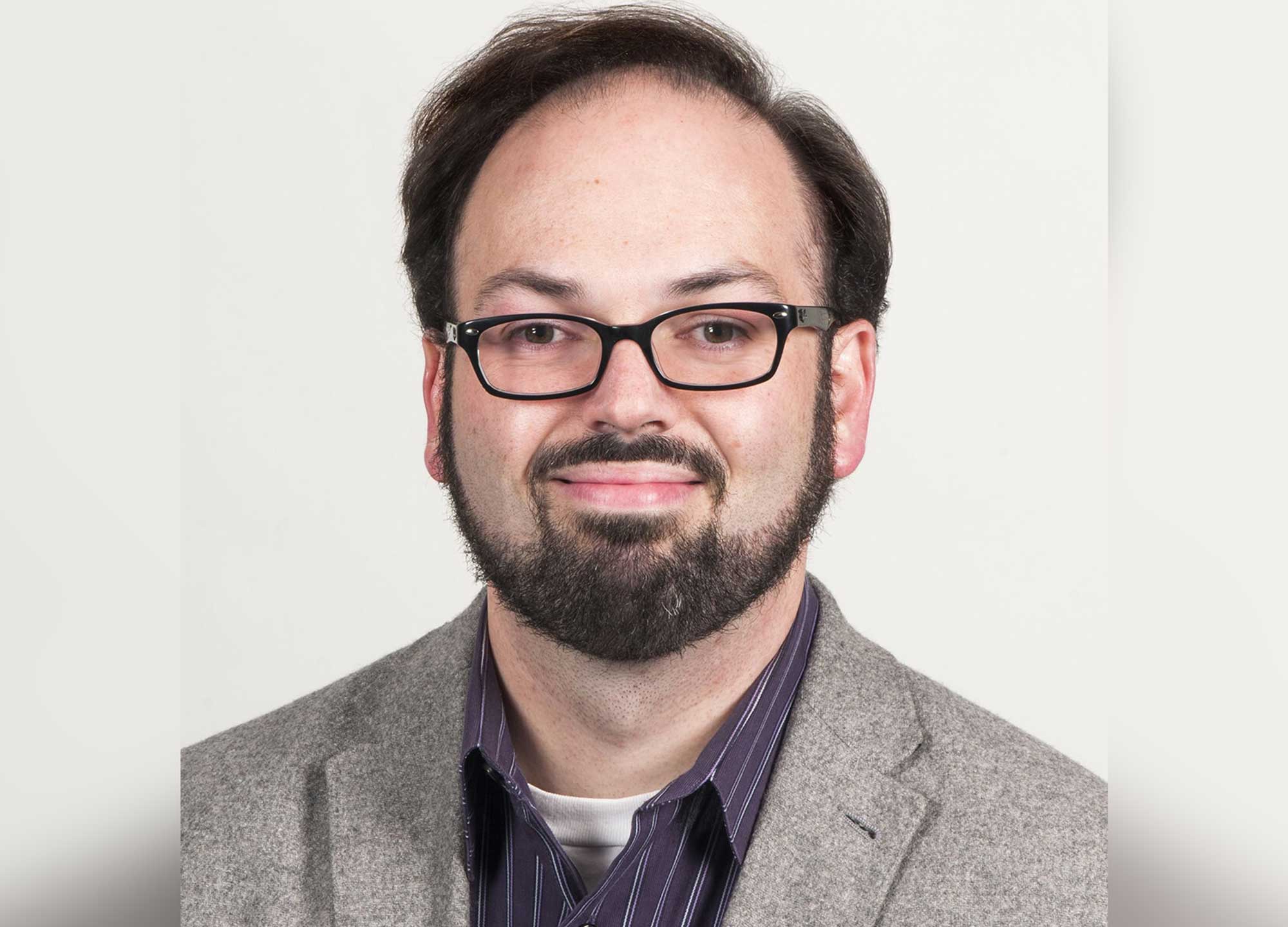 A headshot of an adult wearing dark-colored glasses.