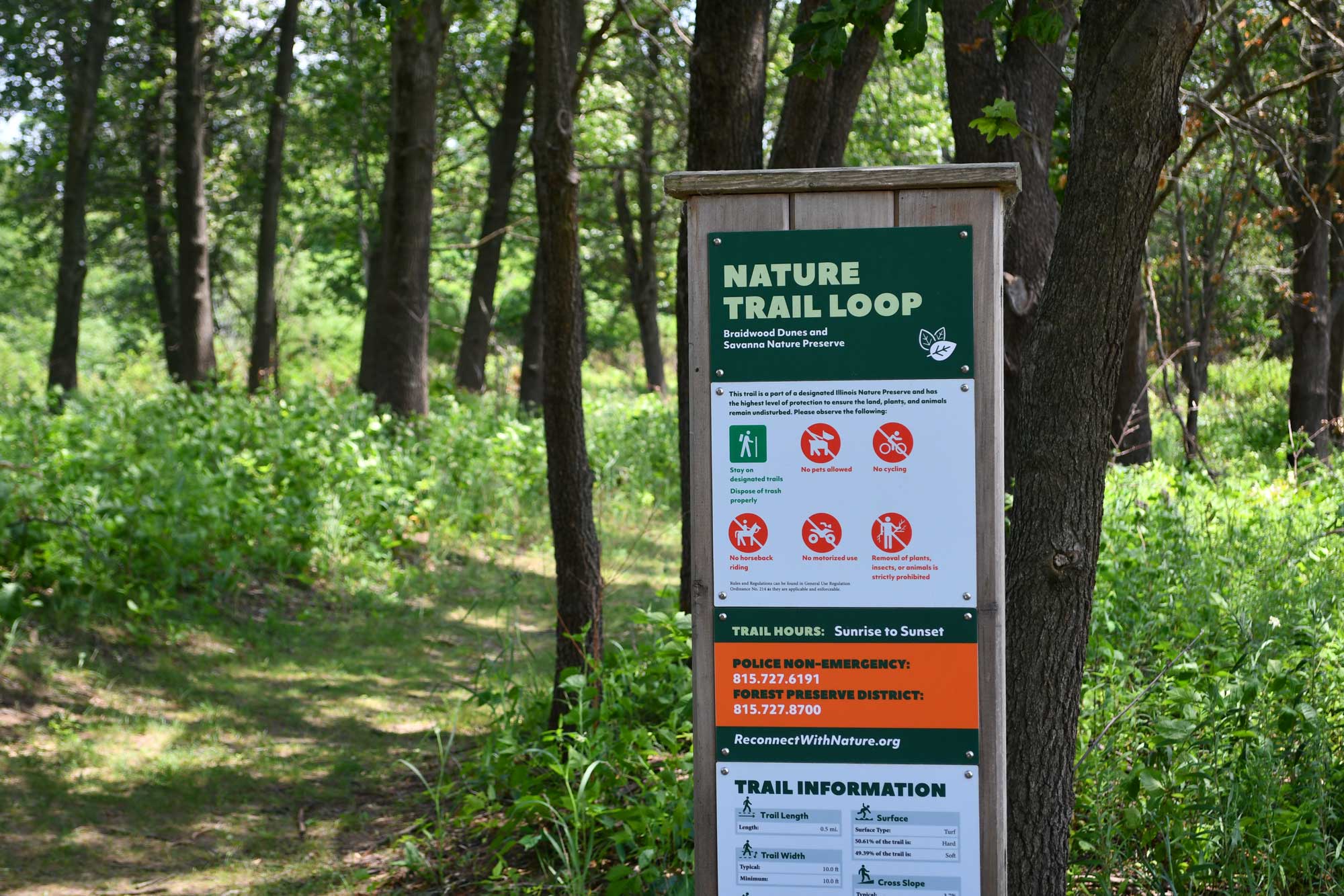 Trail sign in front of a grass trail.