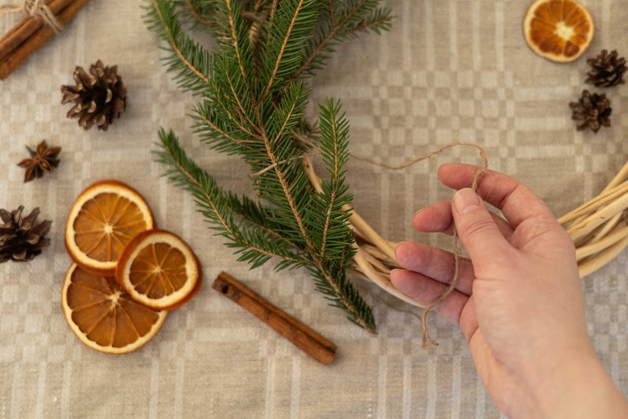 Evergreen branches, dried citrus and pinecones laid out on a table with a wreath.
