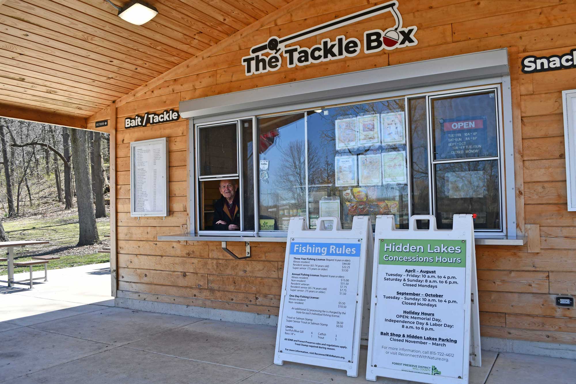 Bait stand with signage and trees in the background.