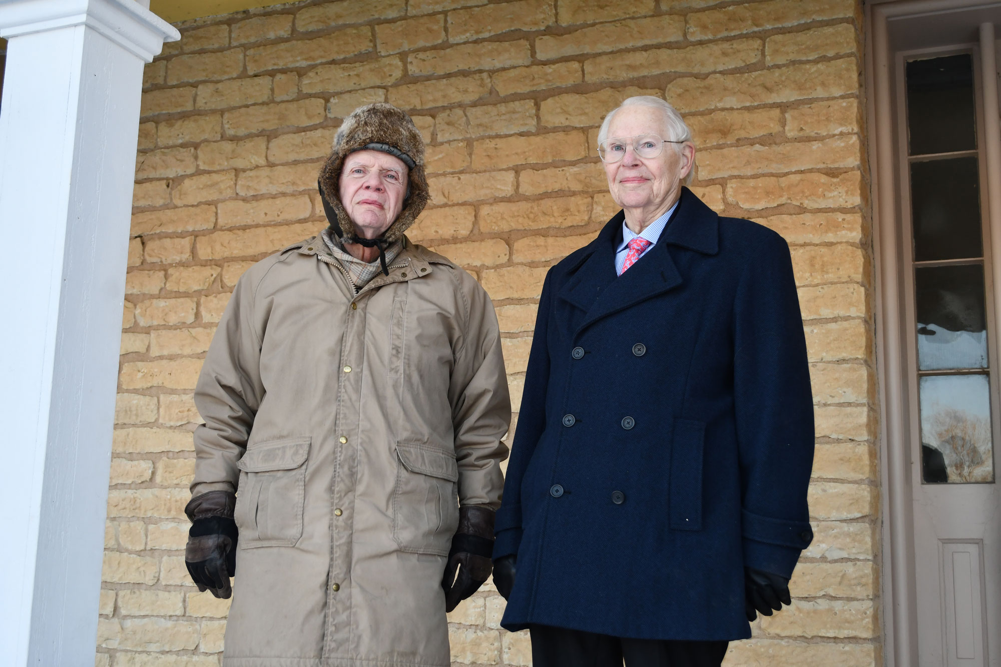 Two people stand on a porch.