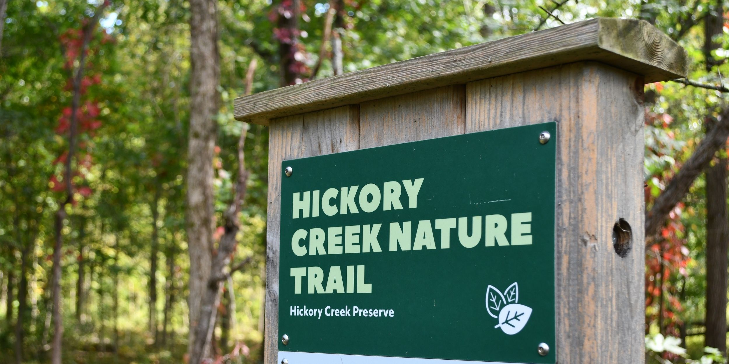 A Hickory Creek trailhead sign surrounded by fall foliage.