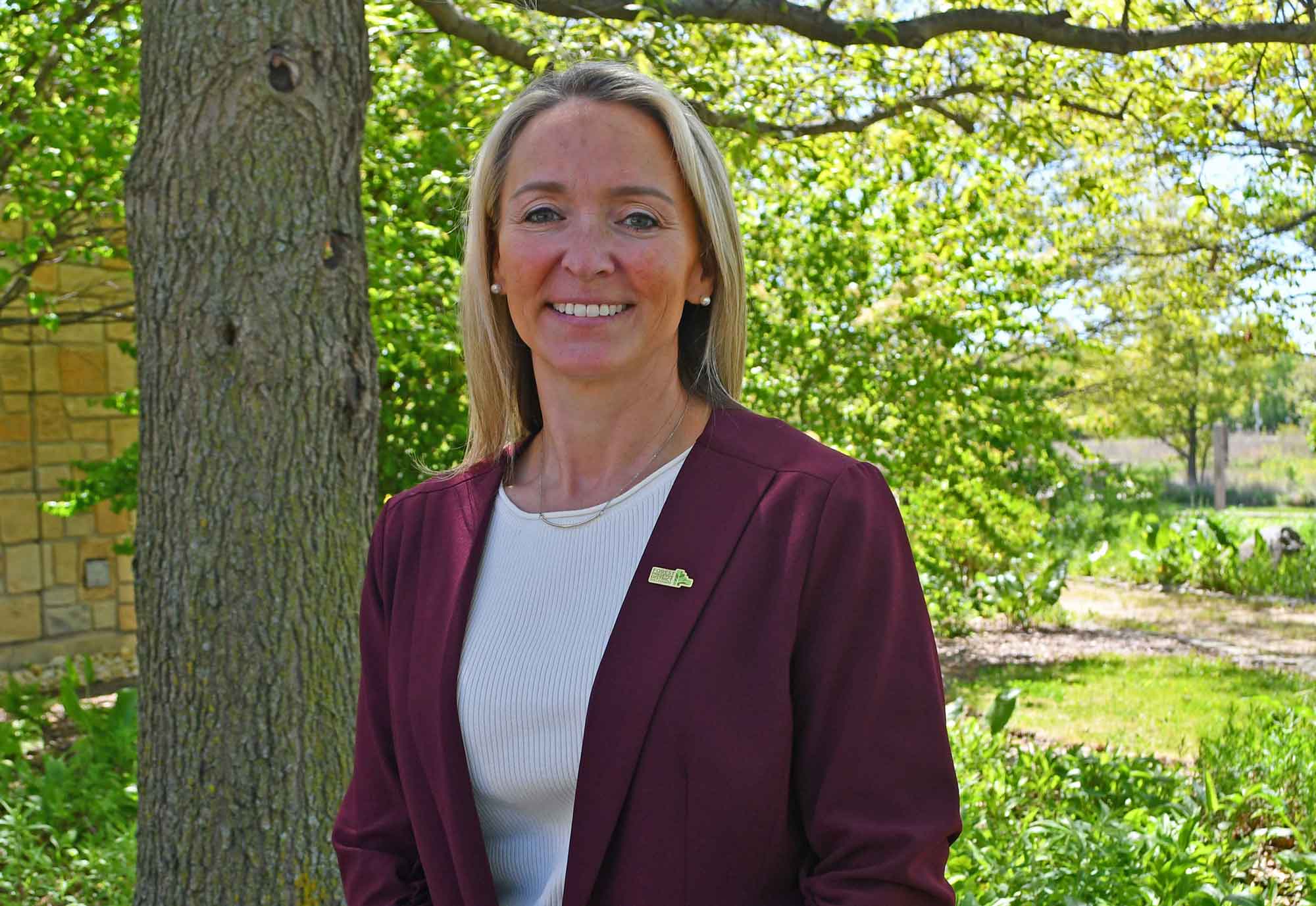 a woman smiling in front of a tree