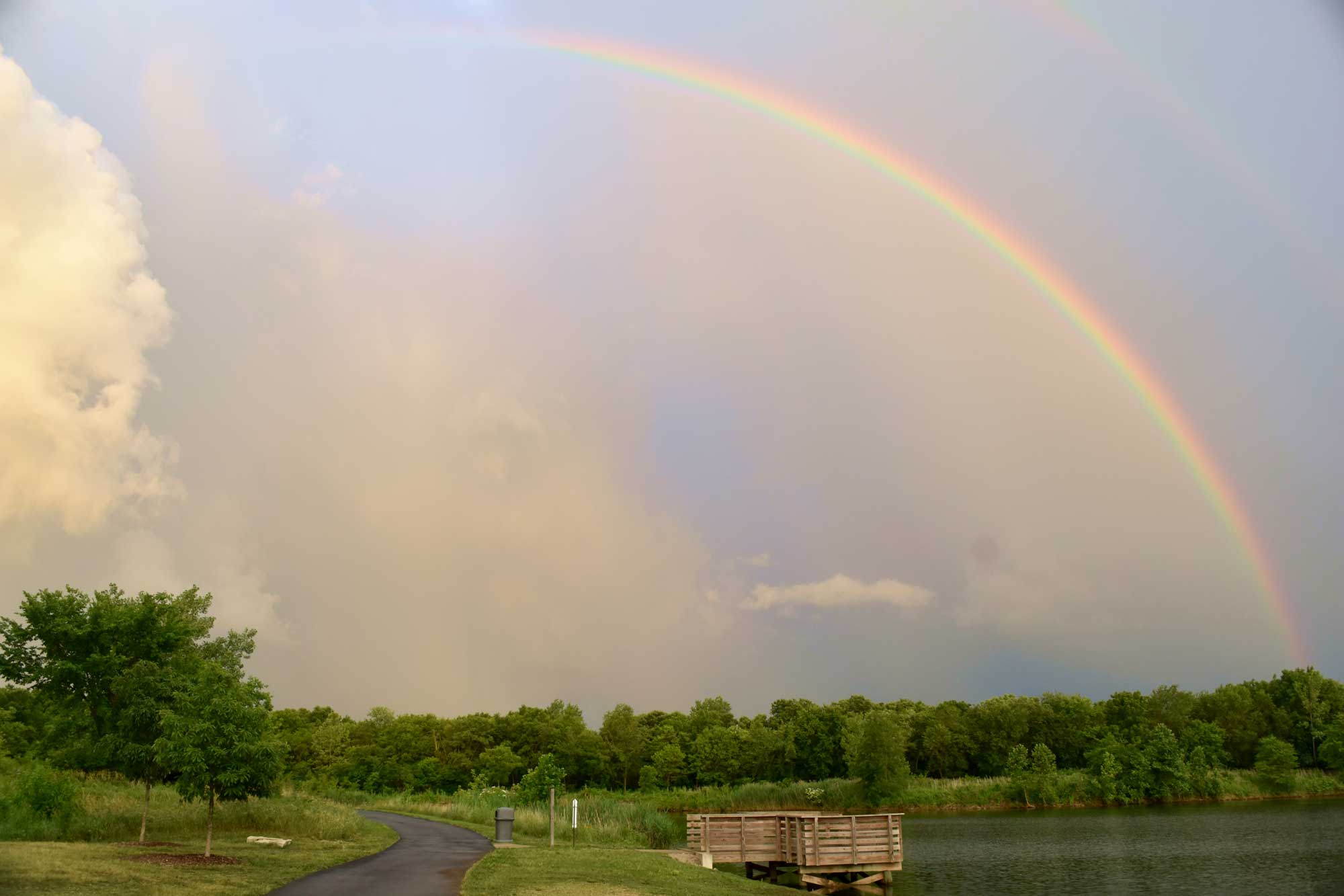 Rainbow in the sky over a lake and trees.