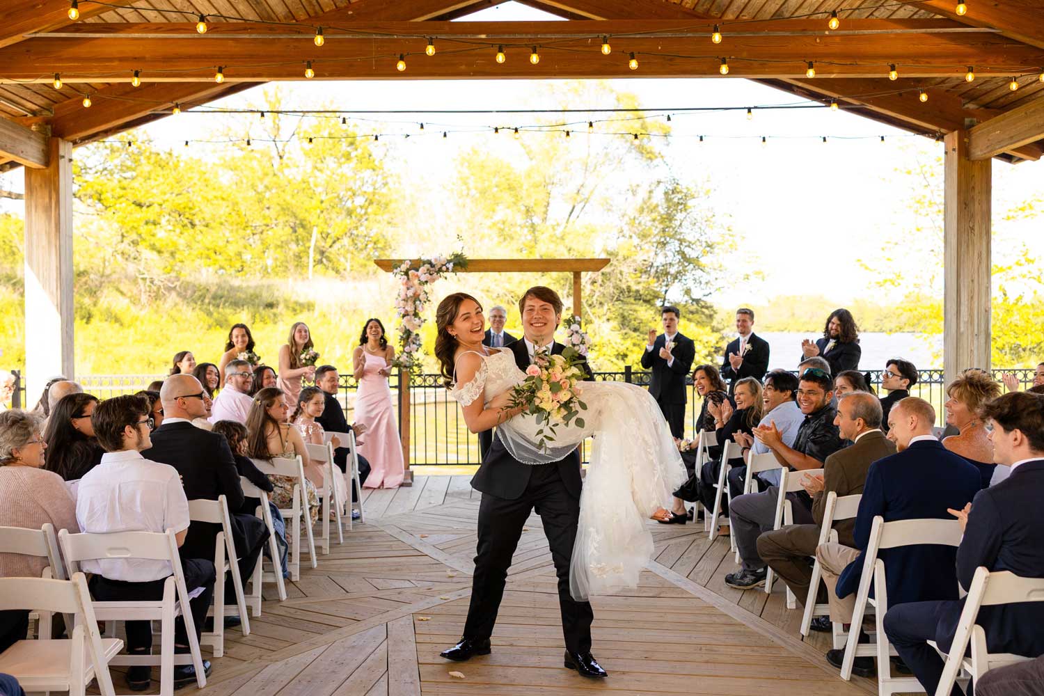 Newly married couple standing in the aisle surrounded by their guests.
