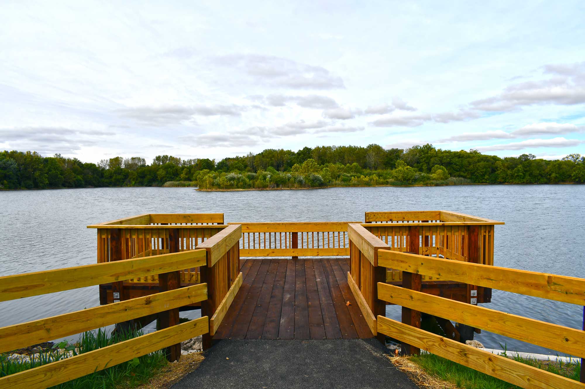 Fishing pier with a lake and trees in the background.