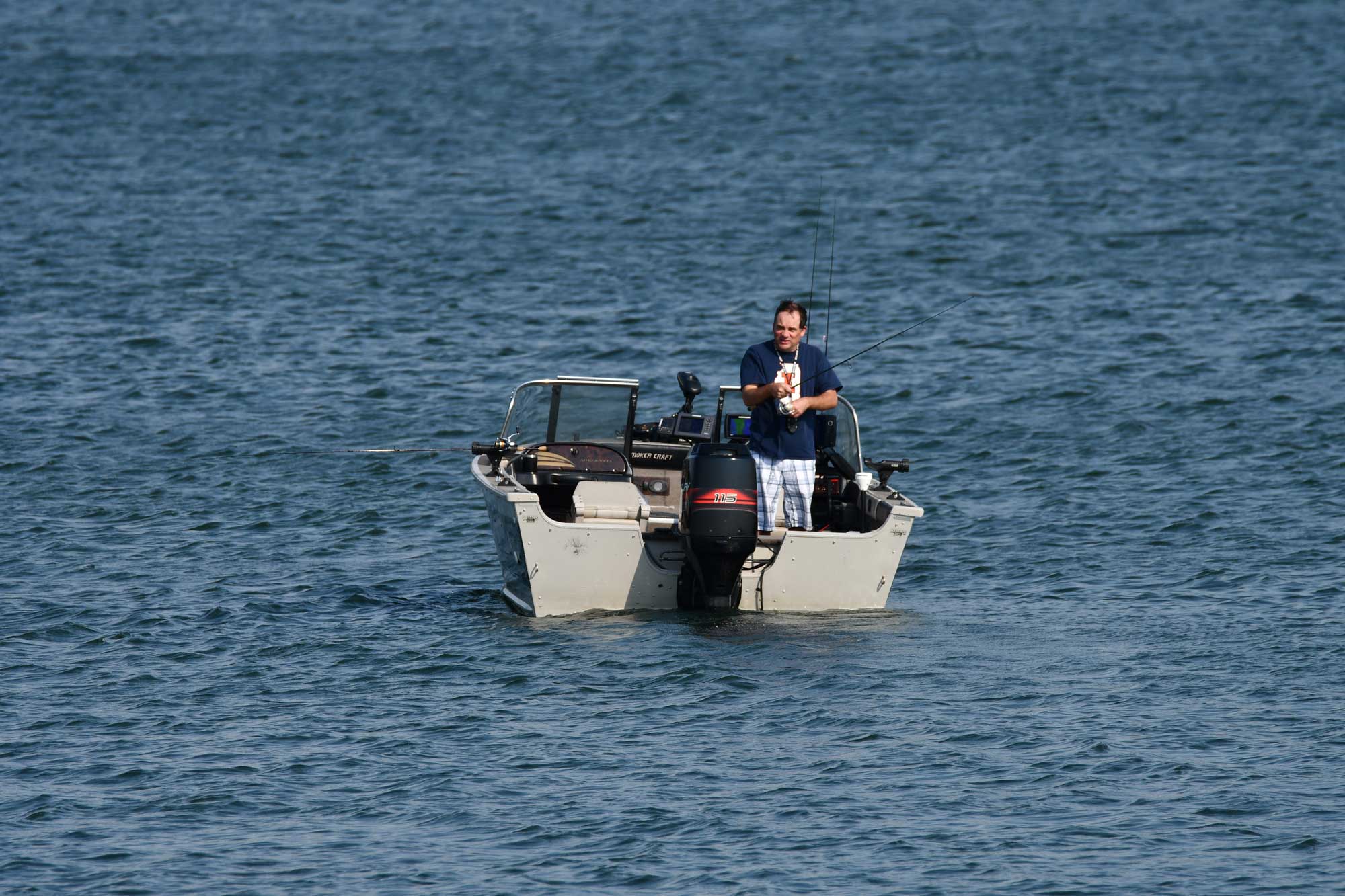 Person standing up in a boat while fishing.