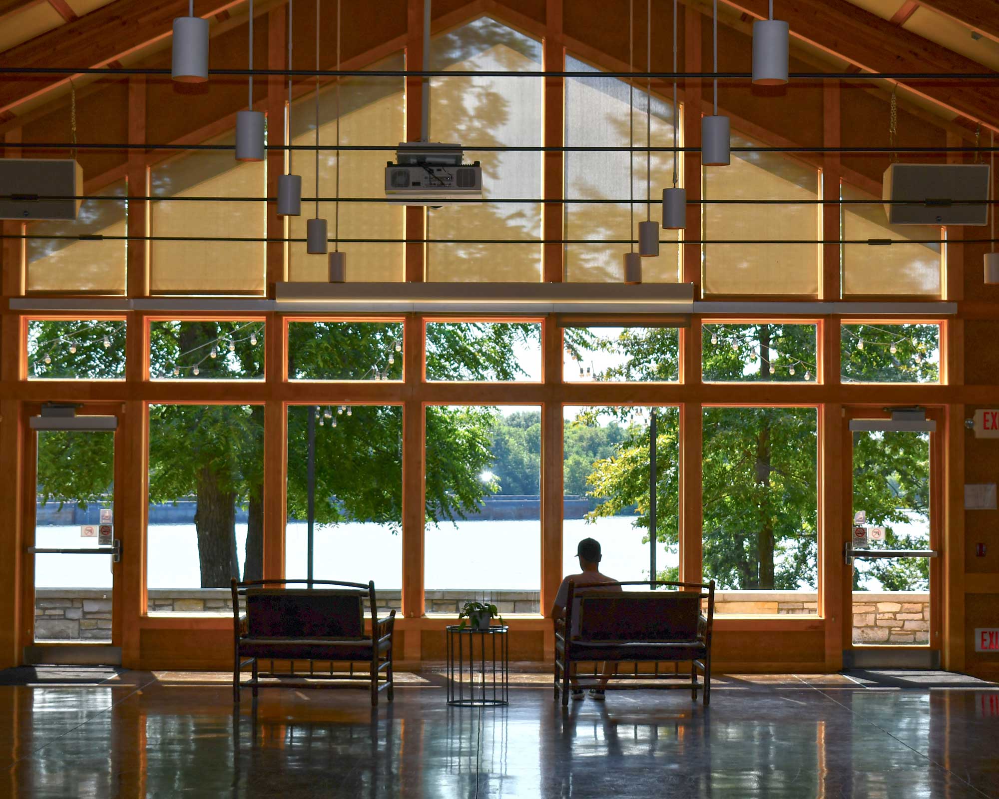 a man sitting on a bench in a room with large windows