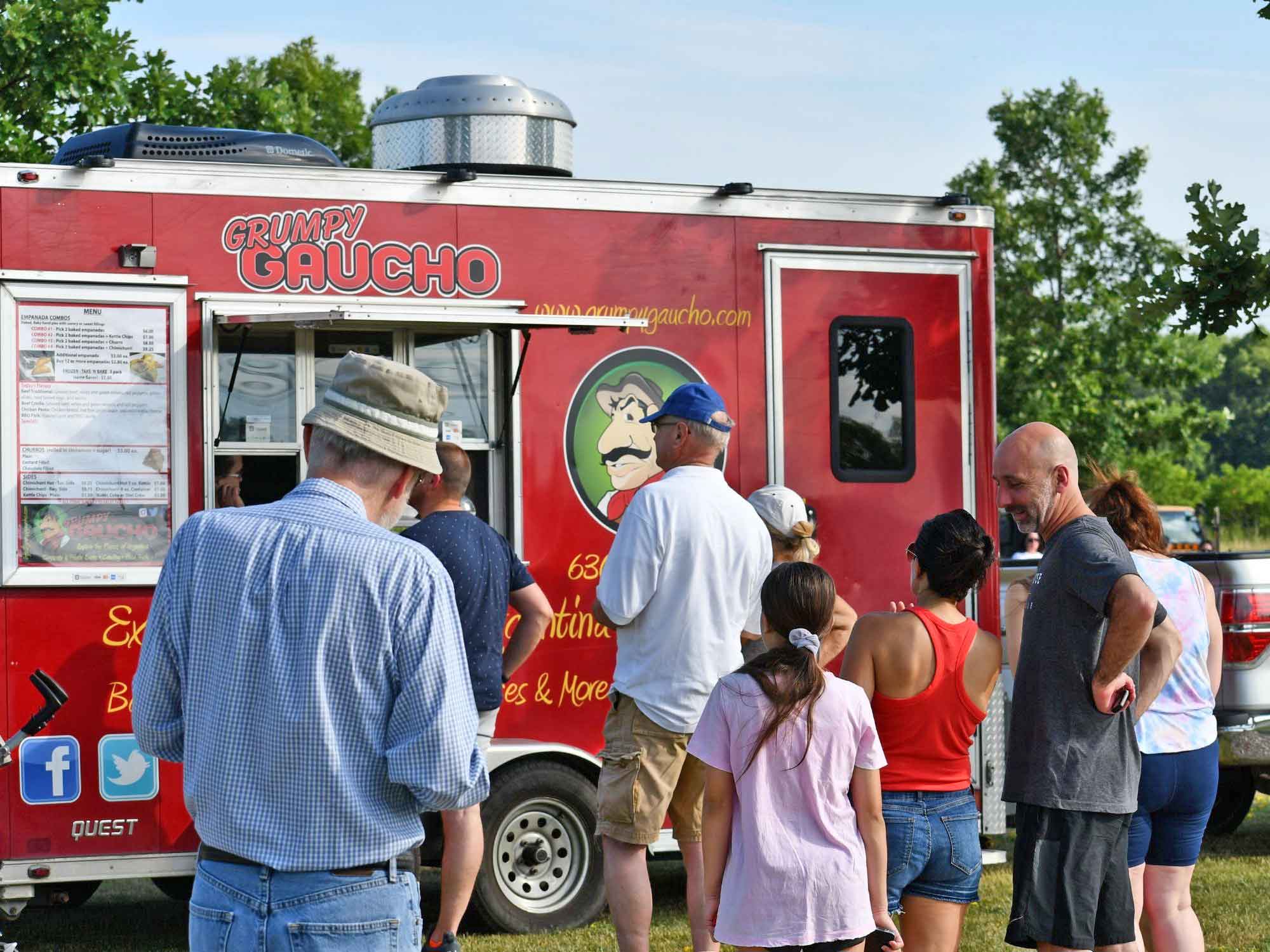 a group of people standing in front of a food truck