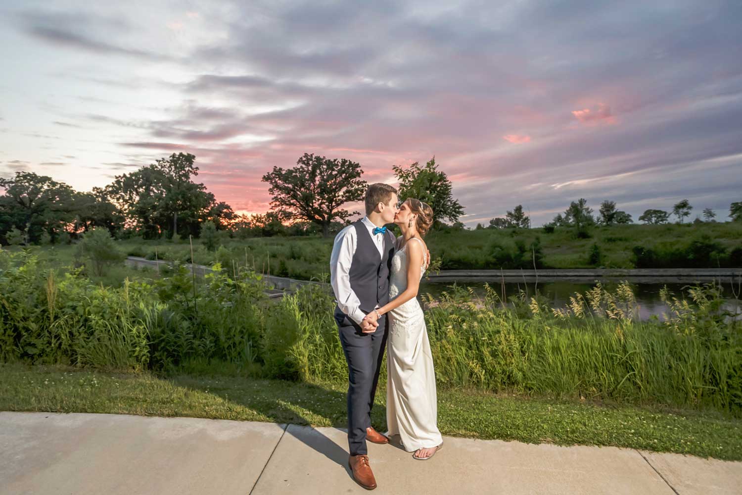 Newly married couple sharing a kiss in front of the sunset.